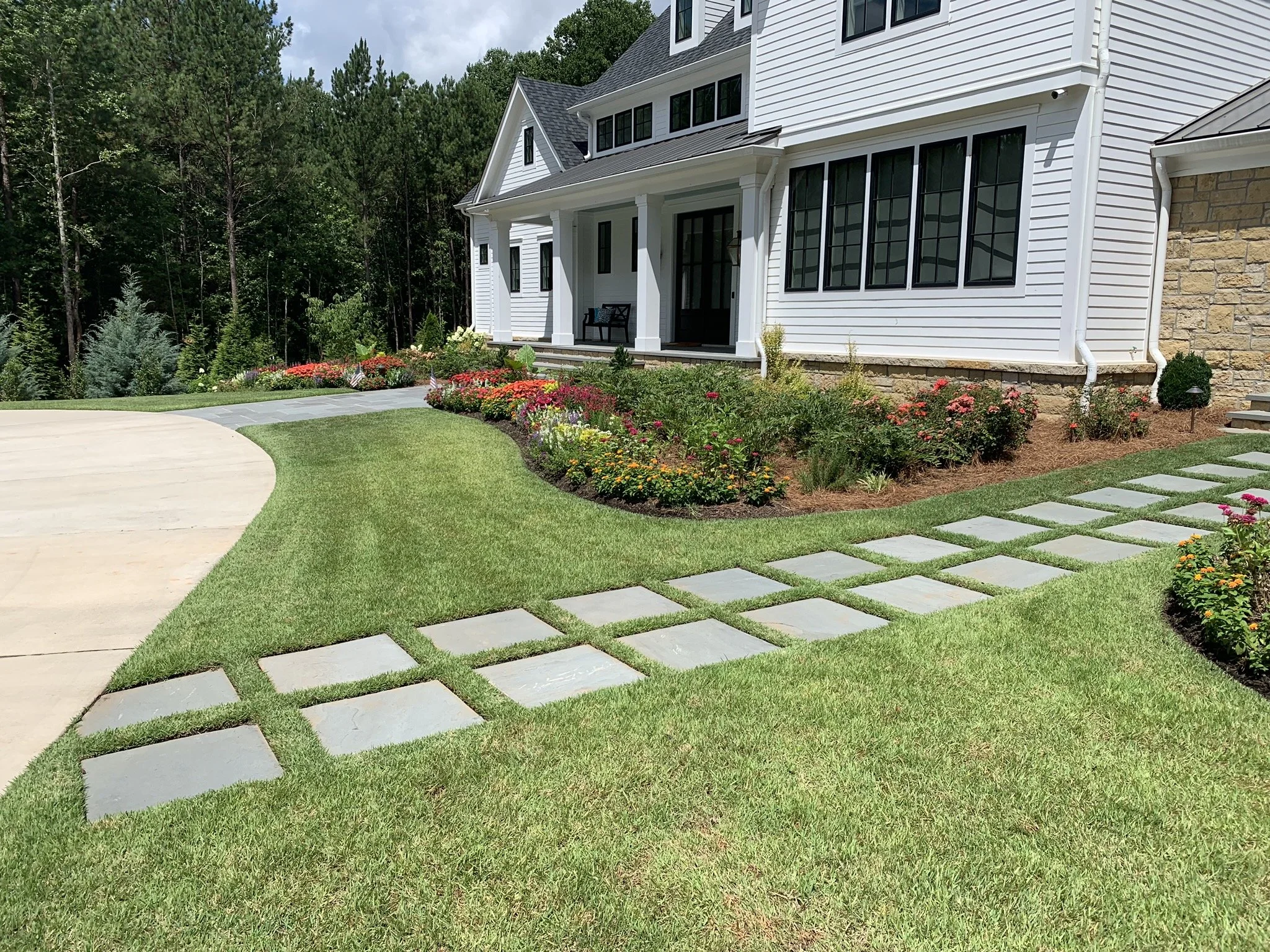 Professionally landscaped front yard in Athens Georgia featuring large format stone steppers, colorful flower beds, and fresh sod installed by Southern Grounds Landscaping