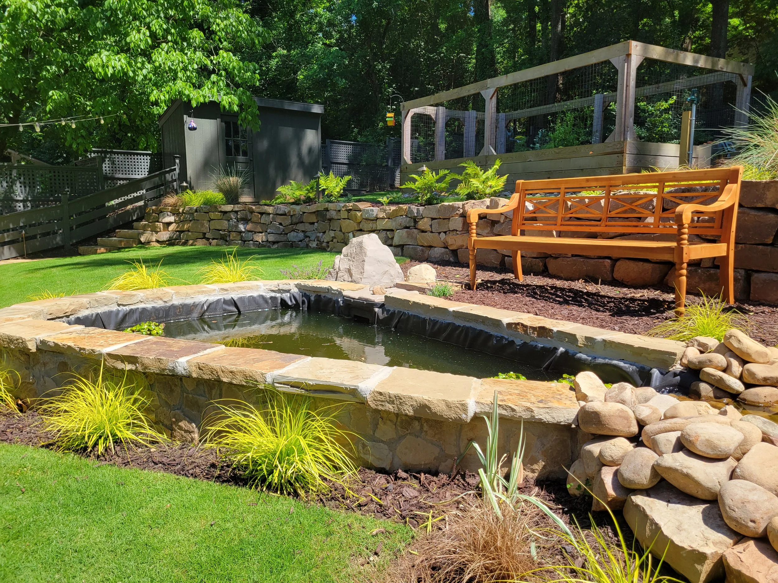 Custom stone waterfall feature with natural rock steps leading to stacked stone patio