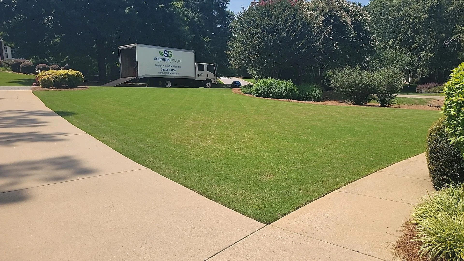 Freshly mowed striped lawn with landscaping service truck parked in residential driveway
