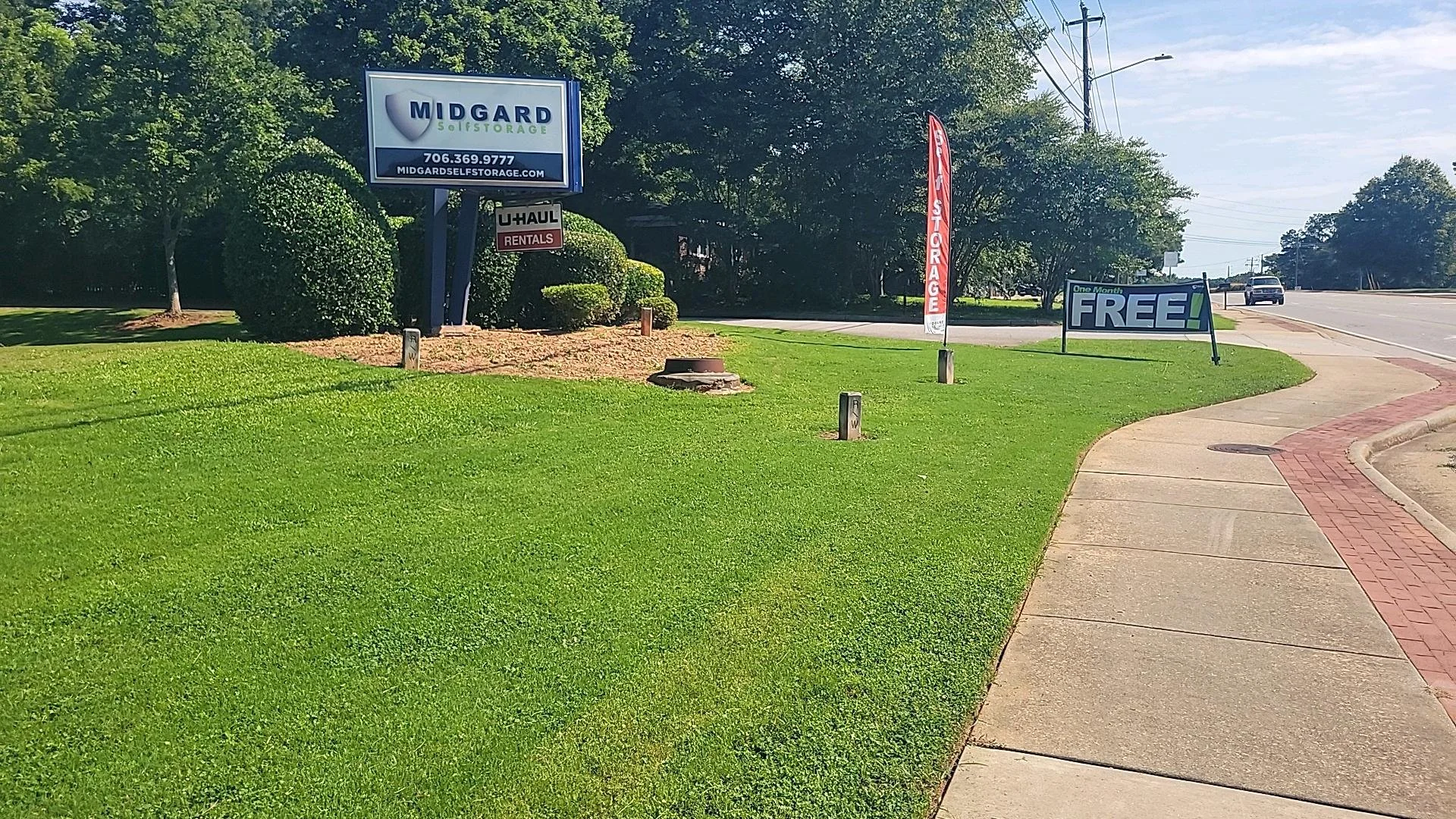 Well-maintained commercial lawn and trimmed shrubs surrounding a business monument sign.