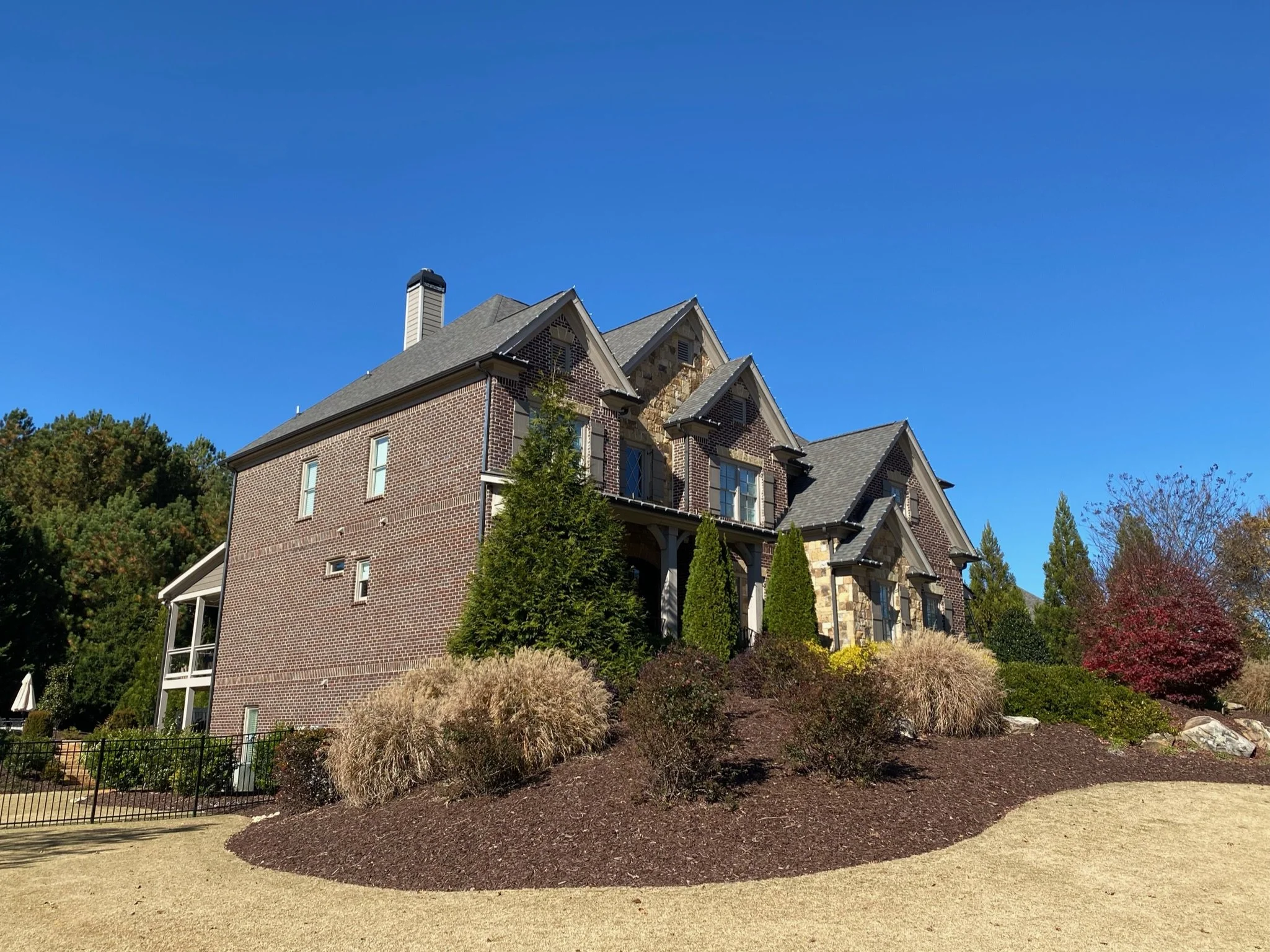 side profile of house with dormant cut grass, mulch bed, and trimmed bushes