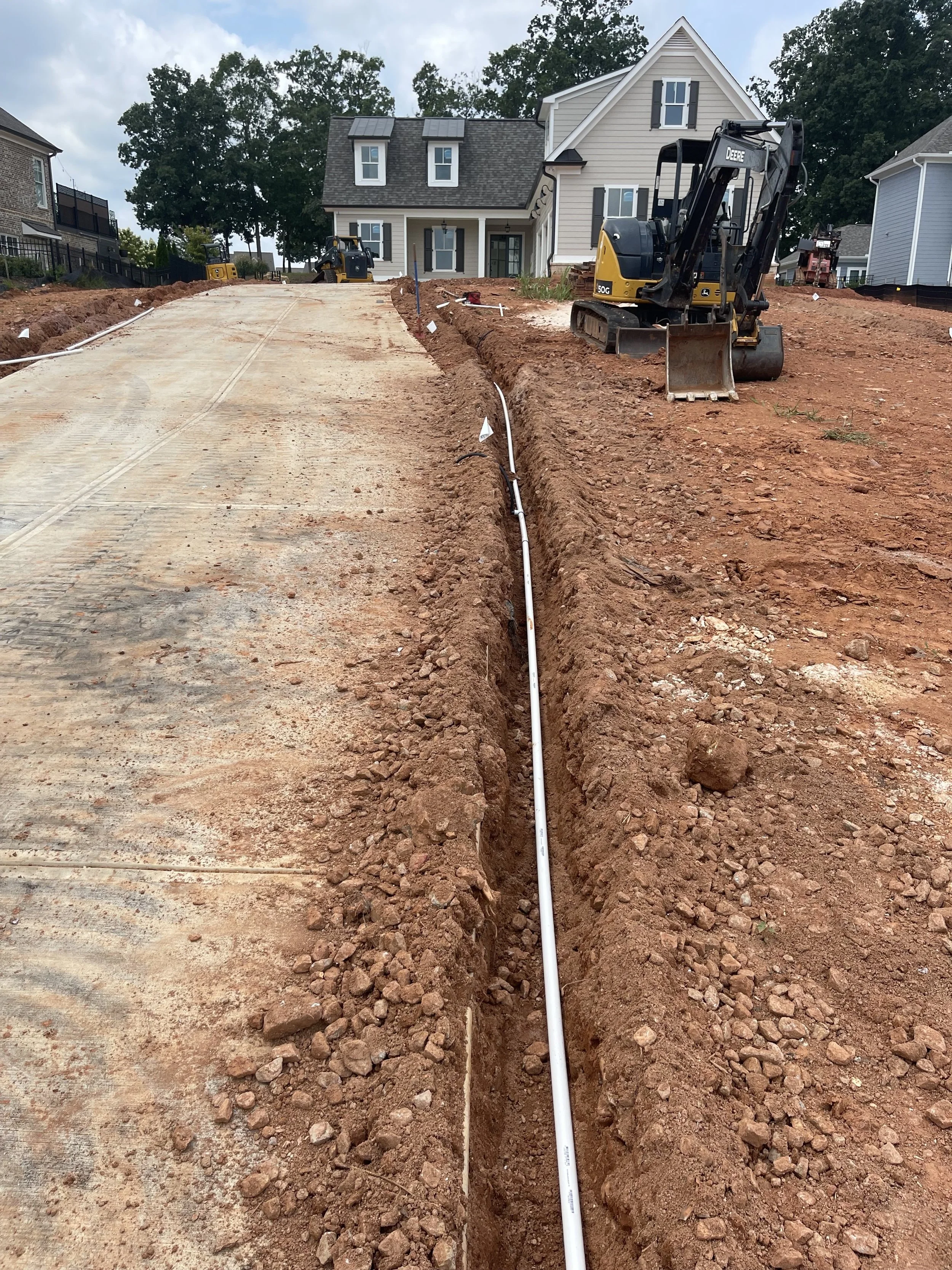 Commercial irrigation pipe trench and PVC supply line installation alongside a concrete pad by Southern Grounds Landscaping in Greensboro Georgia