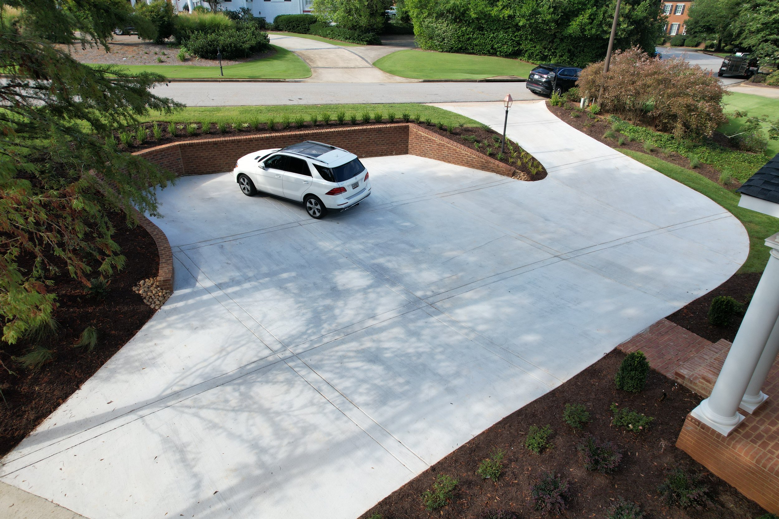 Aerial view of a wide concrete turnaround driveway with brick retaining wall and landscape beds installed by Southern Grounds Landscaping in Athens Georgia