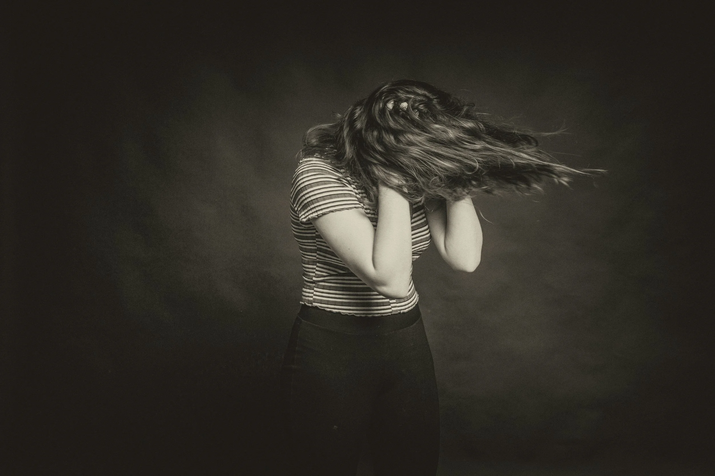 Woman covering her face with hands and hair in motion showing stress