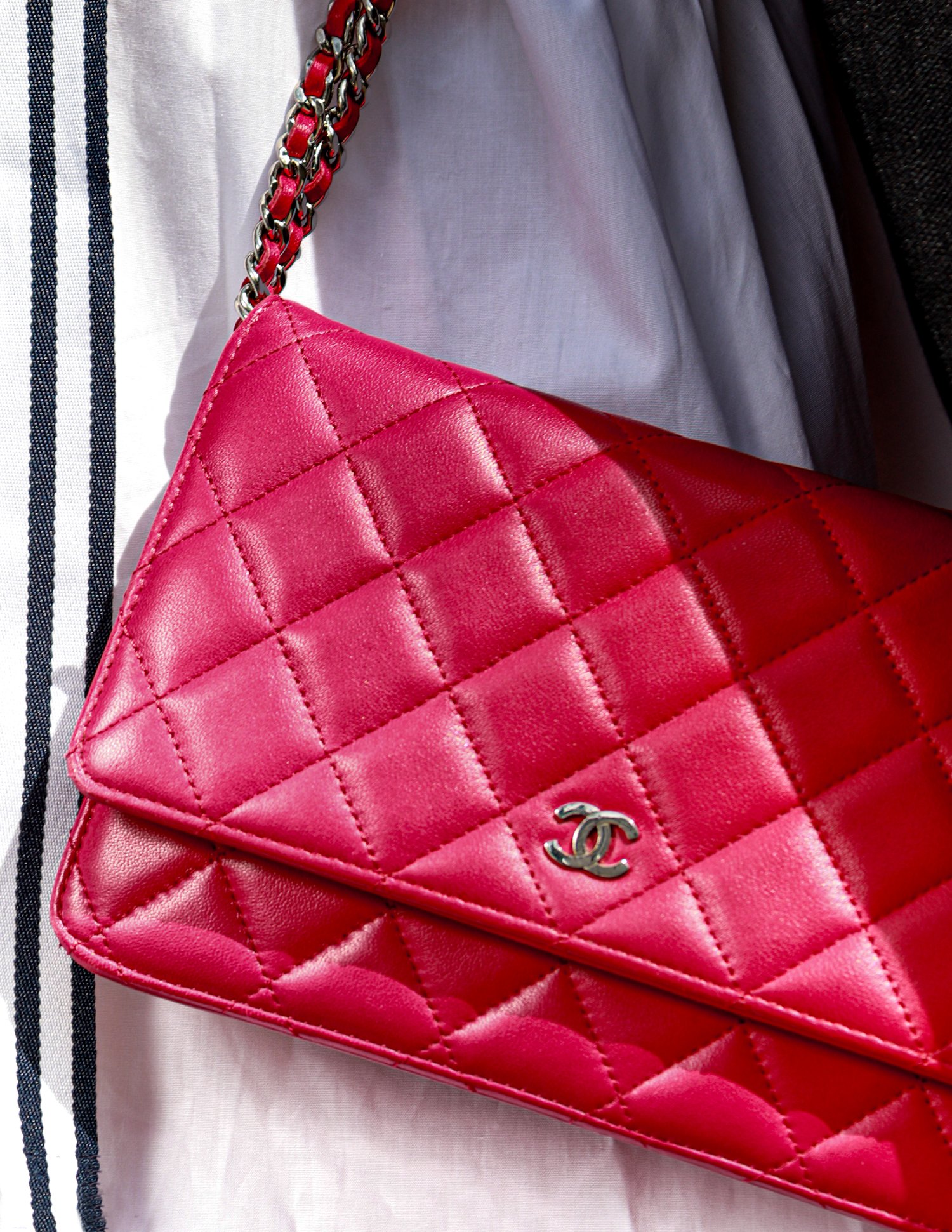 A pink quilted Chanel purse with a silver chain strap and Chanel logo.