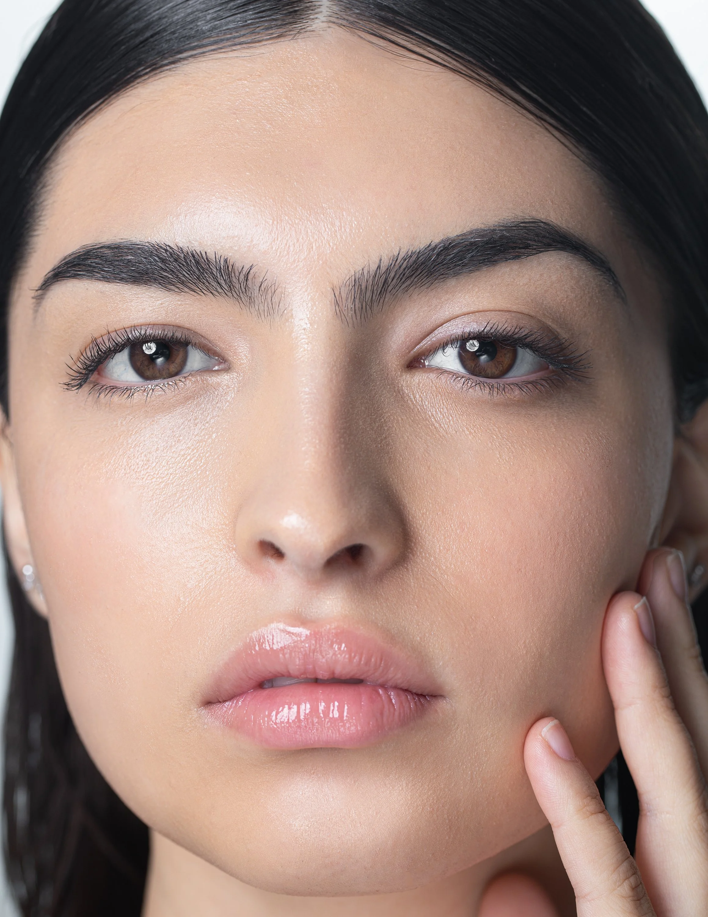 Close-up of a woman's face with well-groomed eyebrows, brown eyes, and natural makeup.