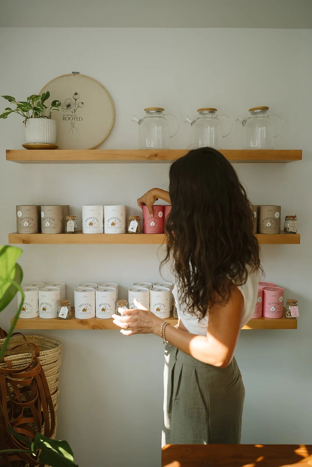 Daniela reaching for a tin of Heart blend on the Growing Up Rooted shelves