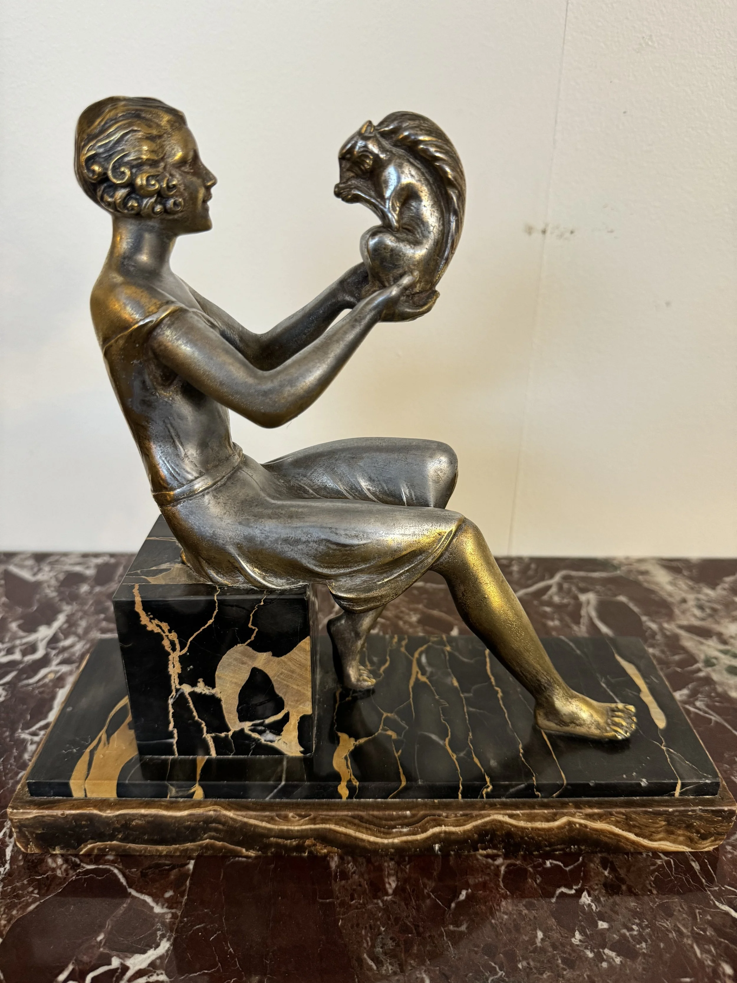 This is a picture of a fabulous French Art Deco silvered and gilt spelter figure of a woman holding a squirrel sitting on a marvellous black marble pedestal, signed J. Dauvergne and made around 1925.