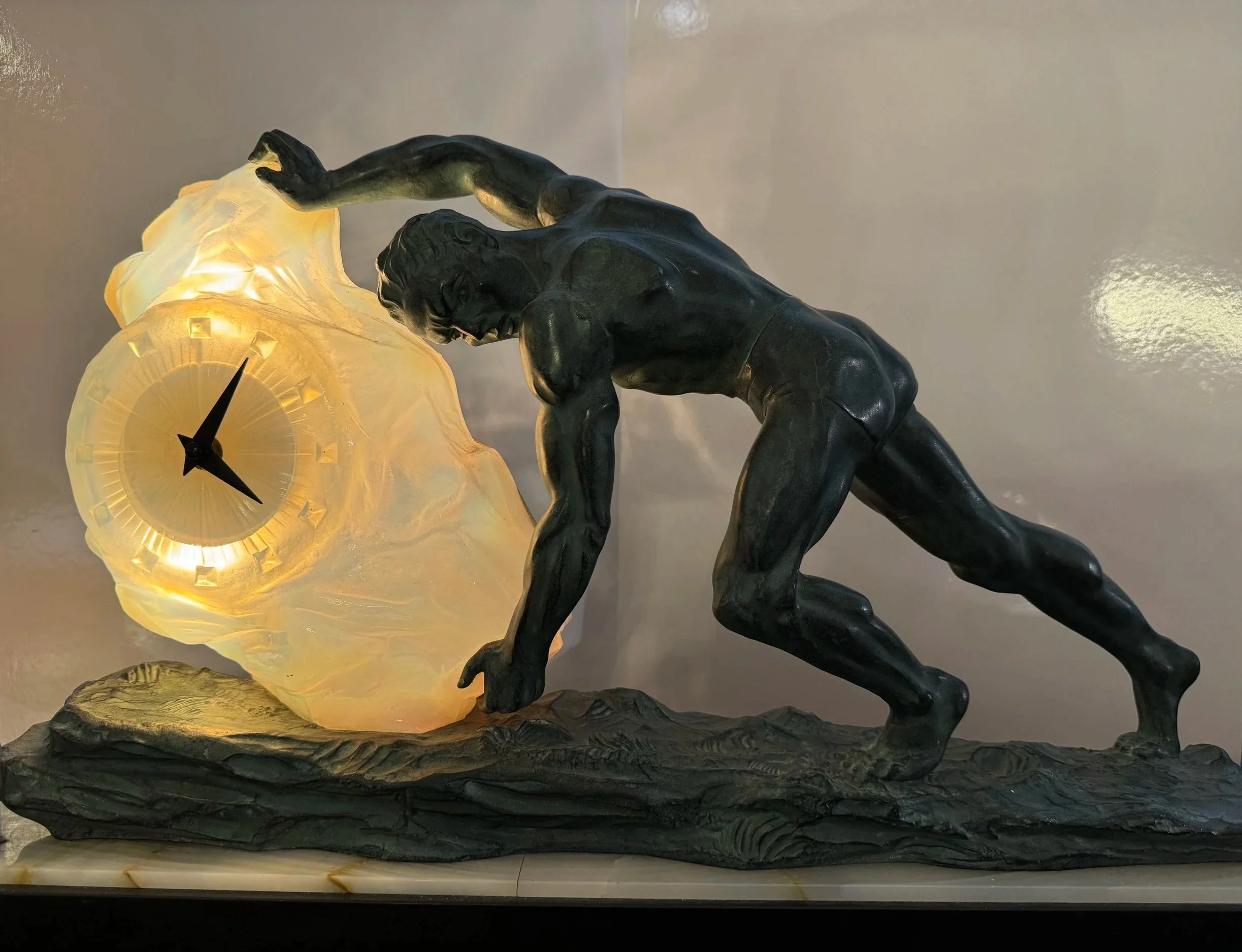 This is a picture of an antique French Art Deco clock  in the form of a man pushing a boulder, made around 1930.