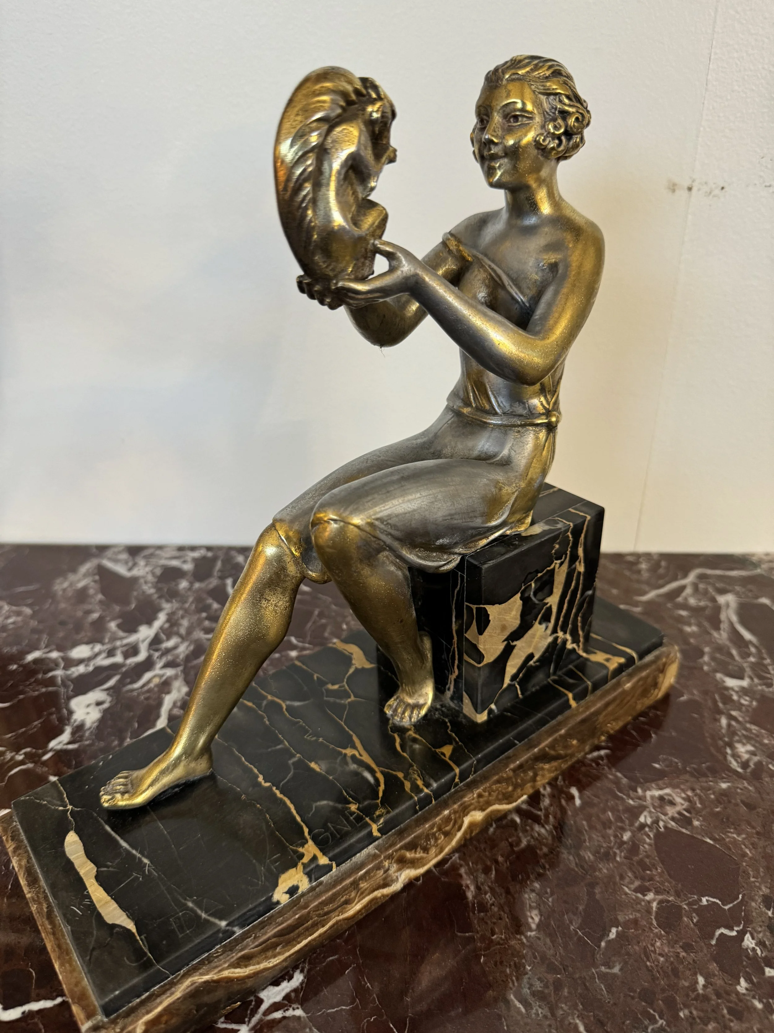 This is a picture of a fabulous French Art Deco silvered and gilt spelter figure of a woman holding a squirrel sitting on a marvellous black marble pedestal, signed J. Dauvergne and made around 1925.
