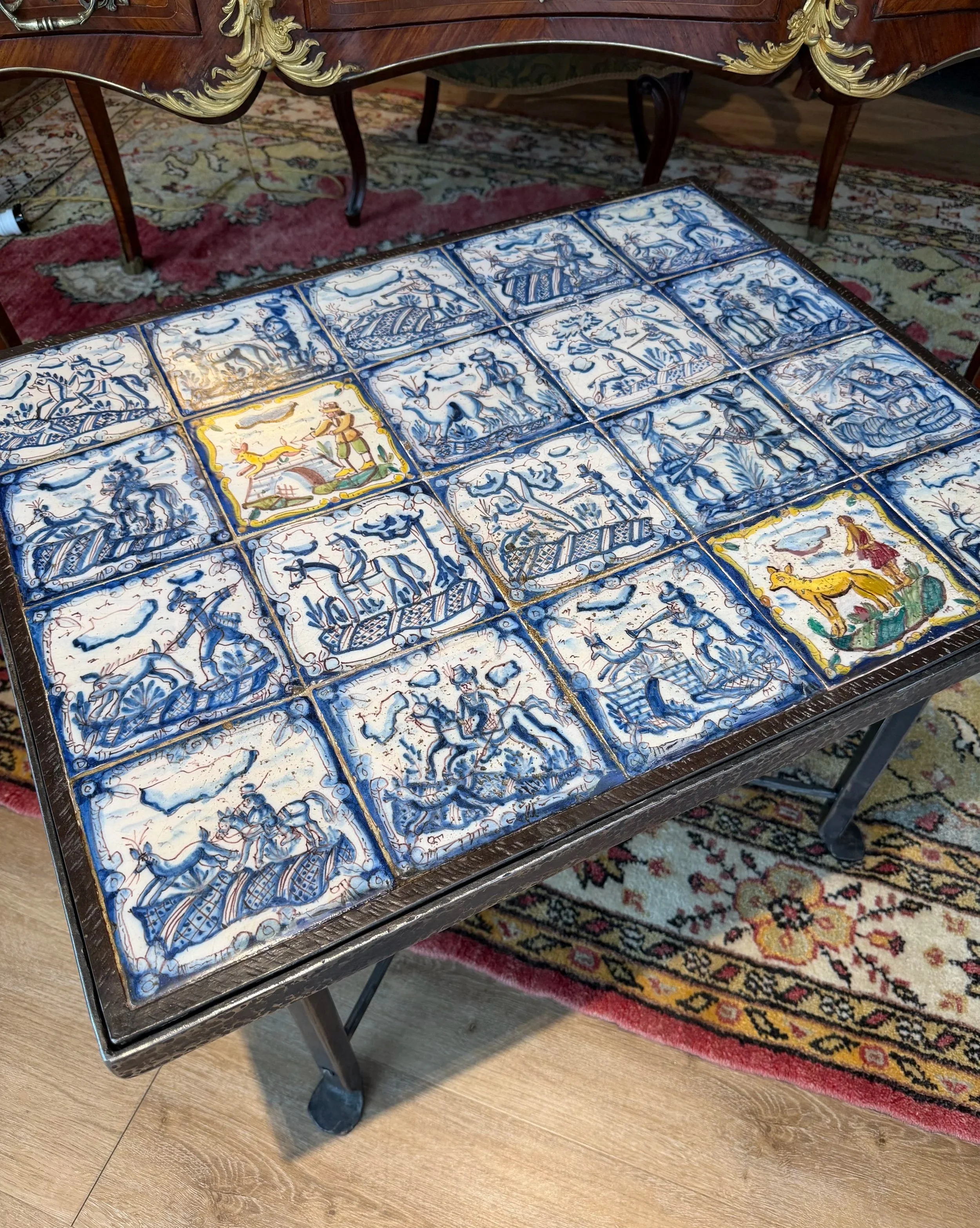 This is a picture of a panel of 20 wonderful 18th century Spanish tiles set into a mid 20th century wrought iron coffee table base.