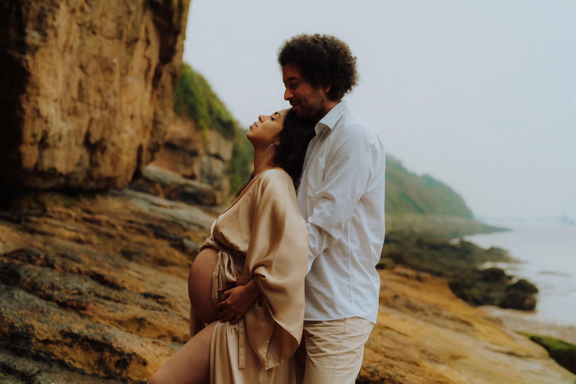 pregnant woman at the beach held by her partner