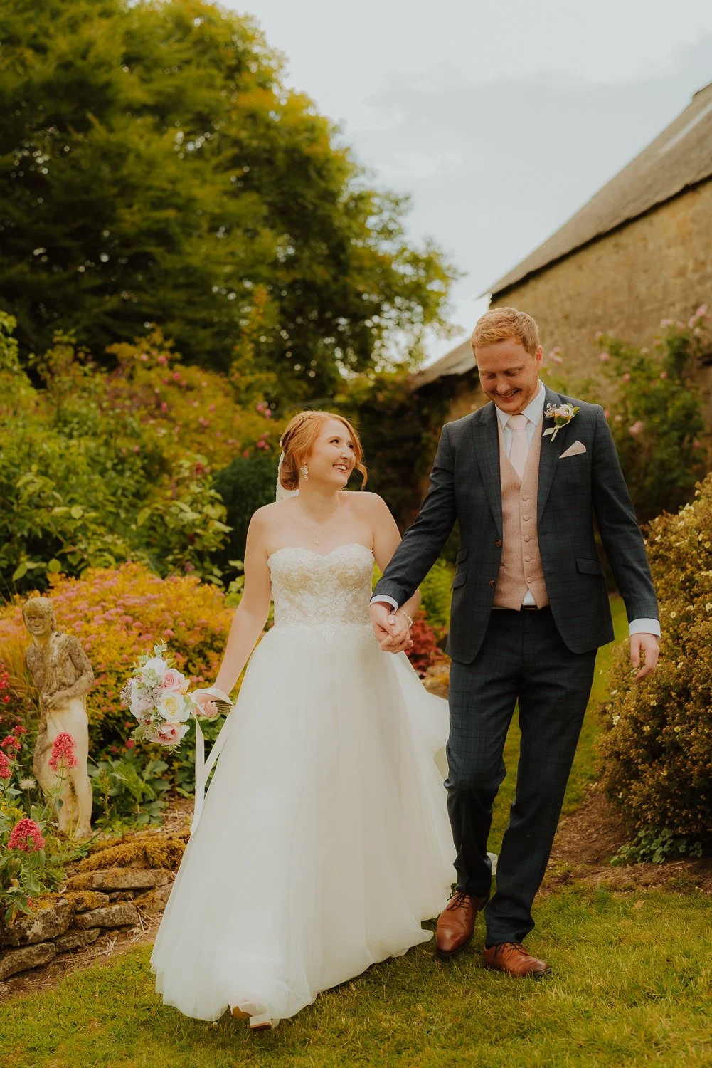 happy couple walking around the grounds on their wedding day in the Cotswolds