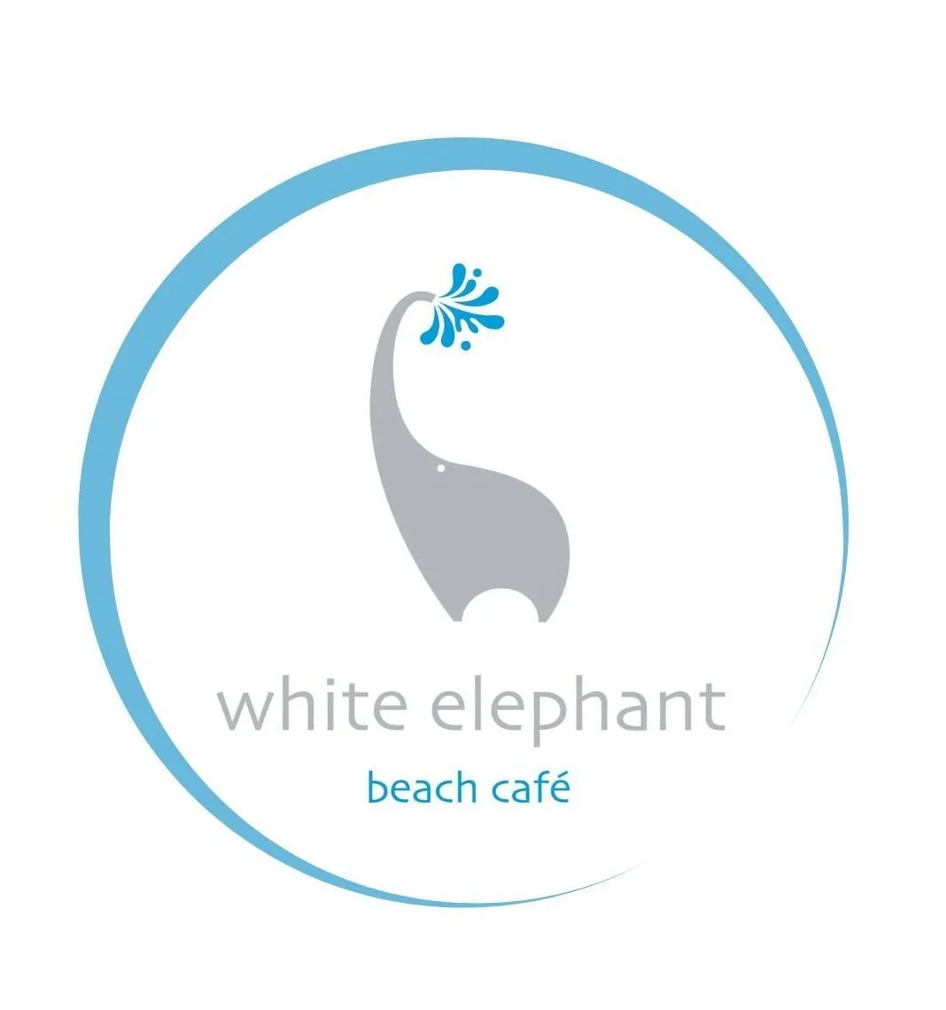 Logo for White Elephant Beach Café featuring a stylized gray elephant with a water splash from its trunk, encircled by a blue outline, with text beneath reading 'white elephant' and 'beach café'.