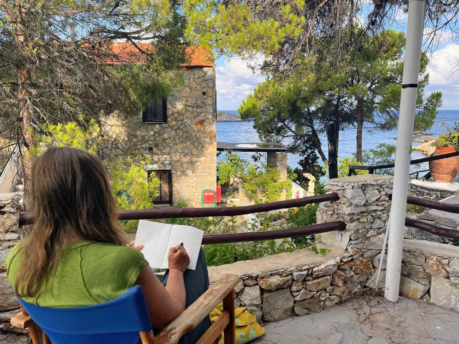 jo sits on a balcony sketching the greek village views on skyross