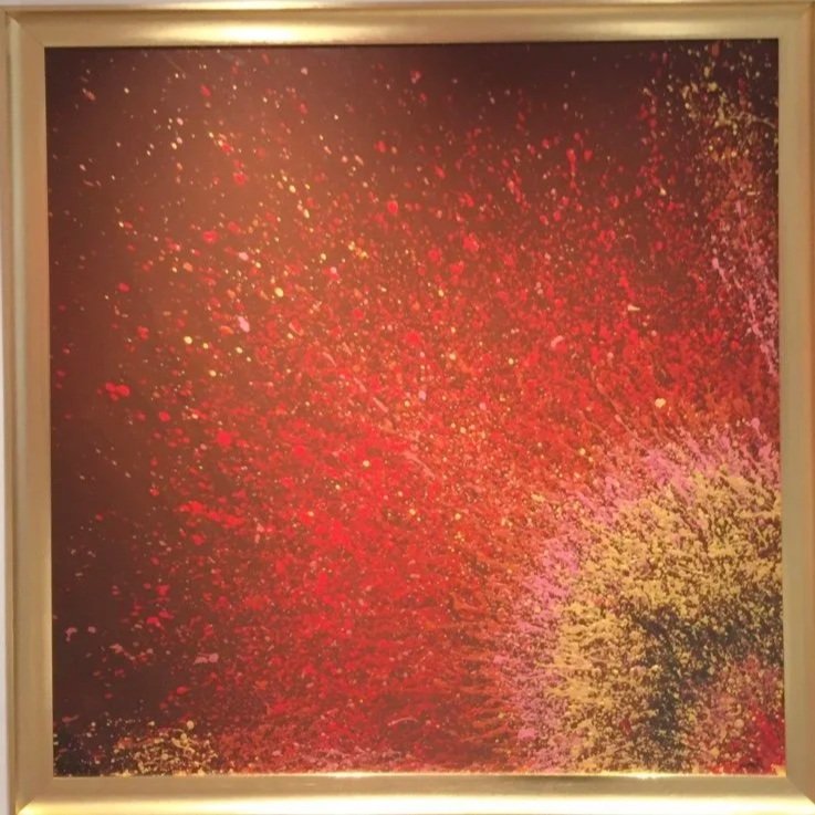 Abstract art with splattered red, pink, and yellow paint on a black background in a square frame.