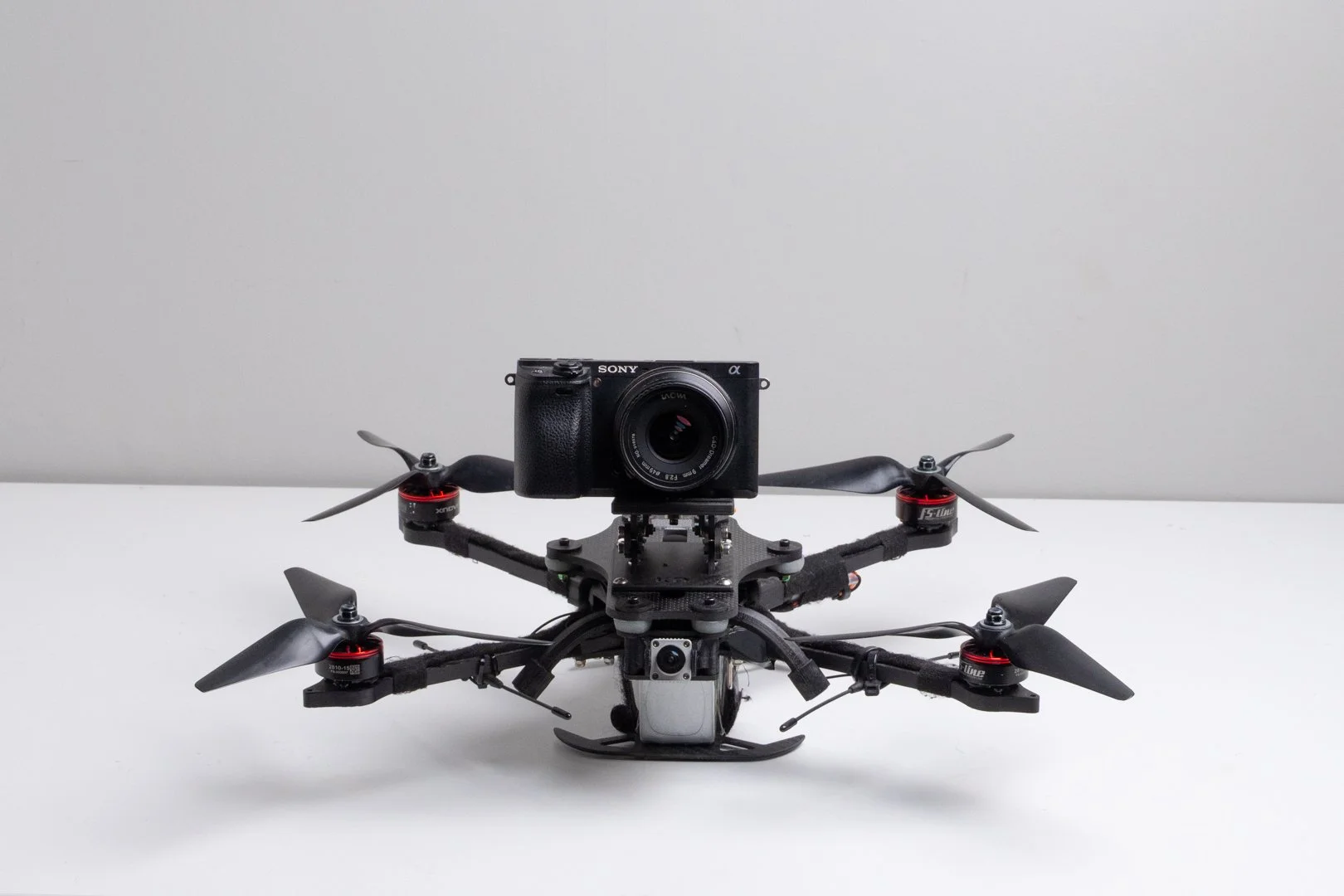FPV Quadcopter drone with a camera mounted on top, placed on a white surface against a plain background.