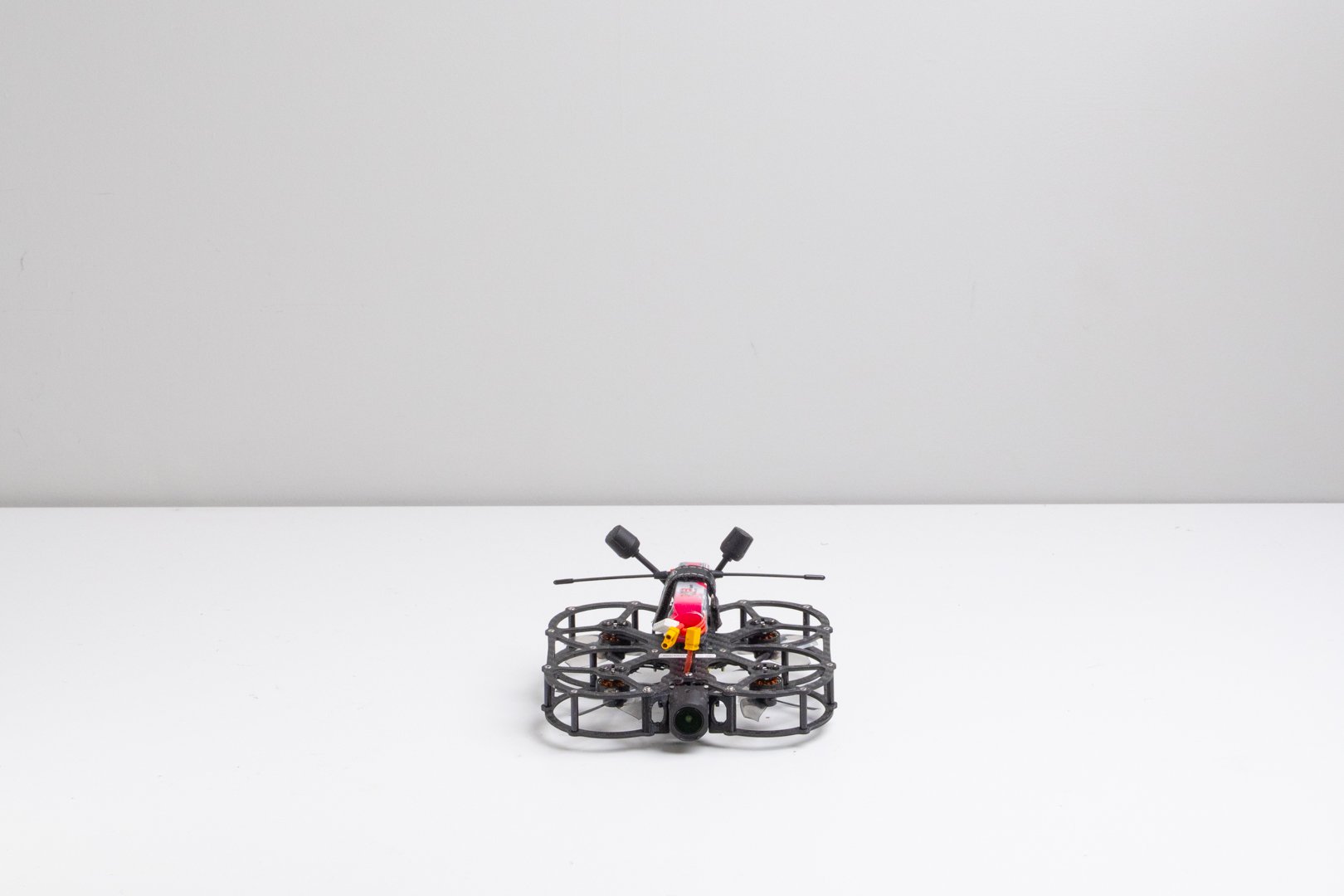 Two drones with cameras on a white surface, one with orange propellers and the other with a GoPro camera.