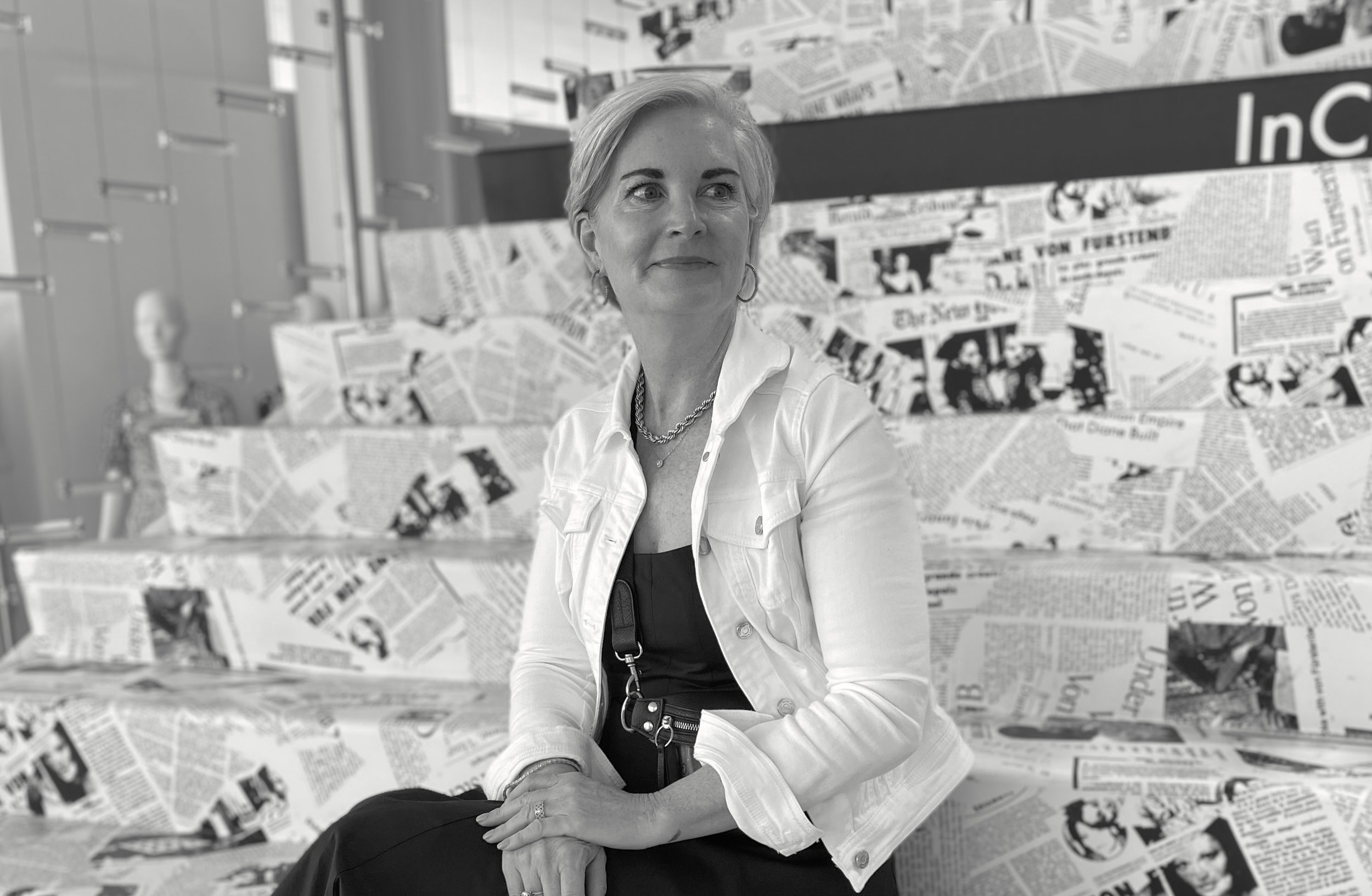 Christina sits on newspaper covered stairs, looking off camera to the right
