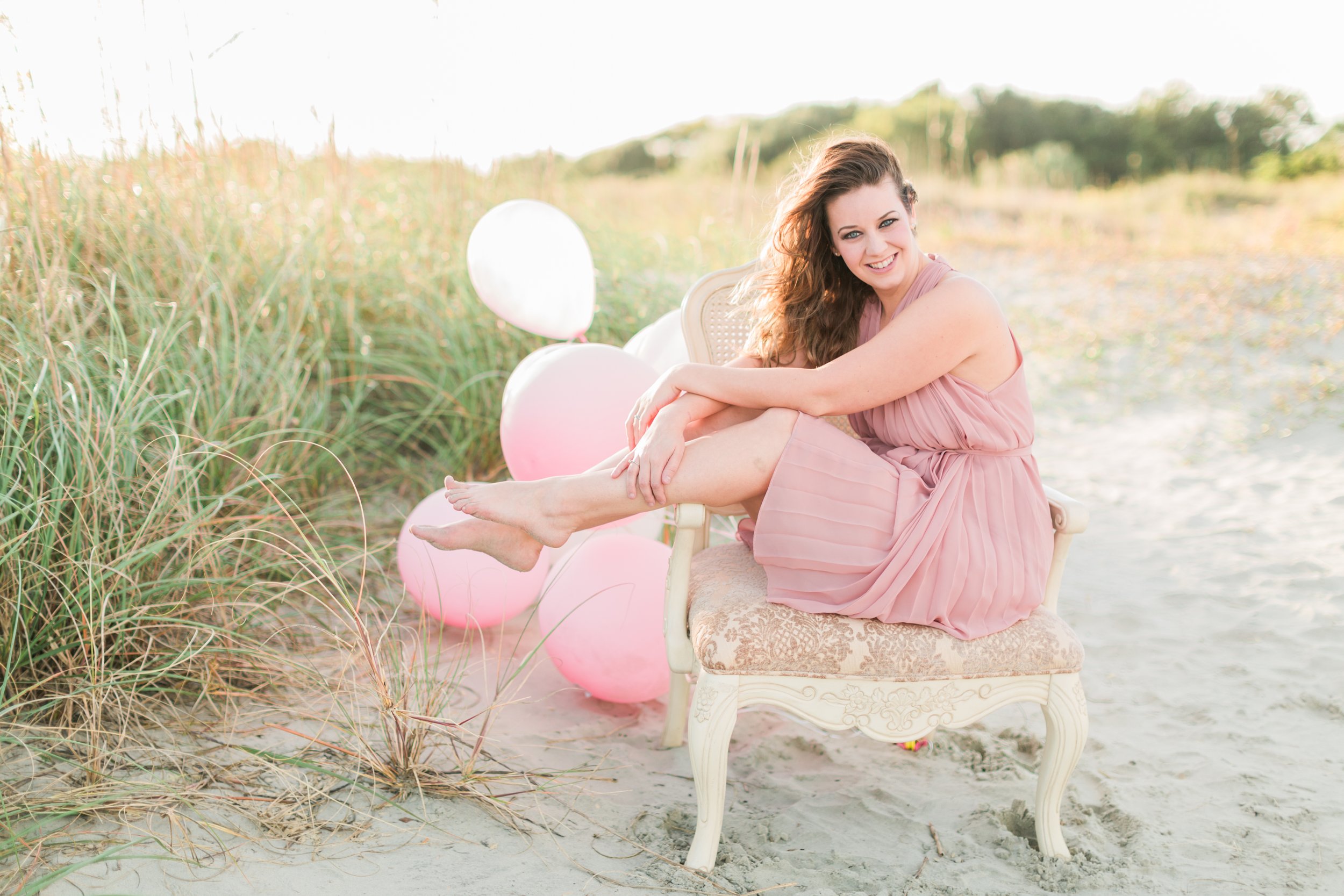 Woman in pink sitting in chair with balloons for her 30th birthday