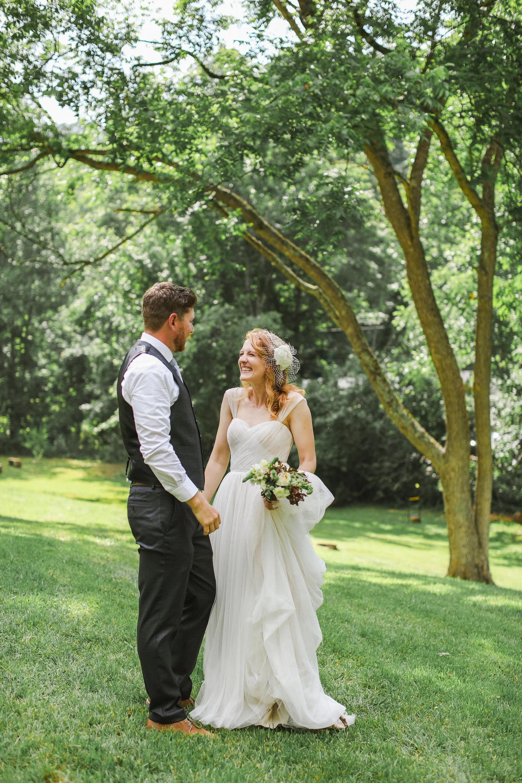 A bride and groom holding hands and smiling at each other outdoors at intimate wedding in Greenville, SC