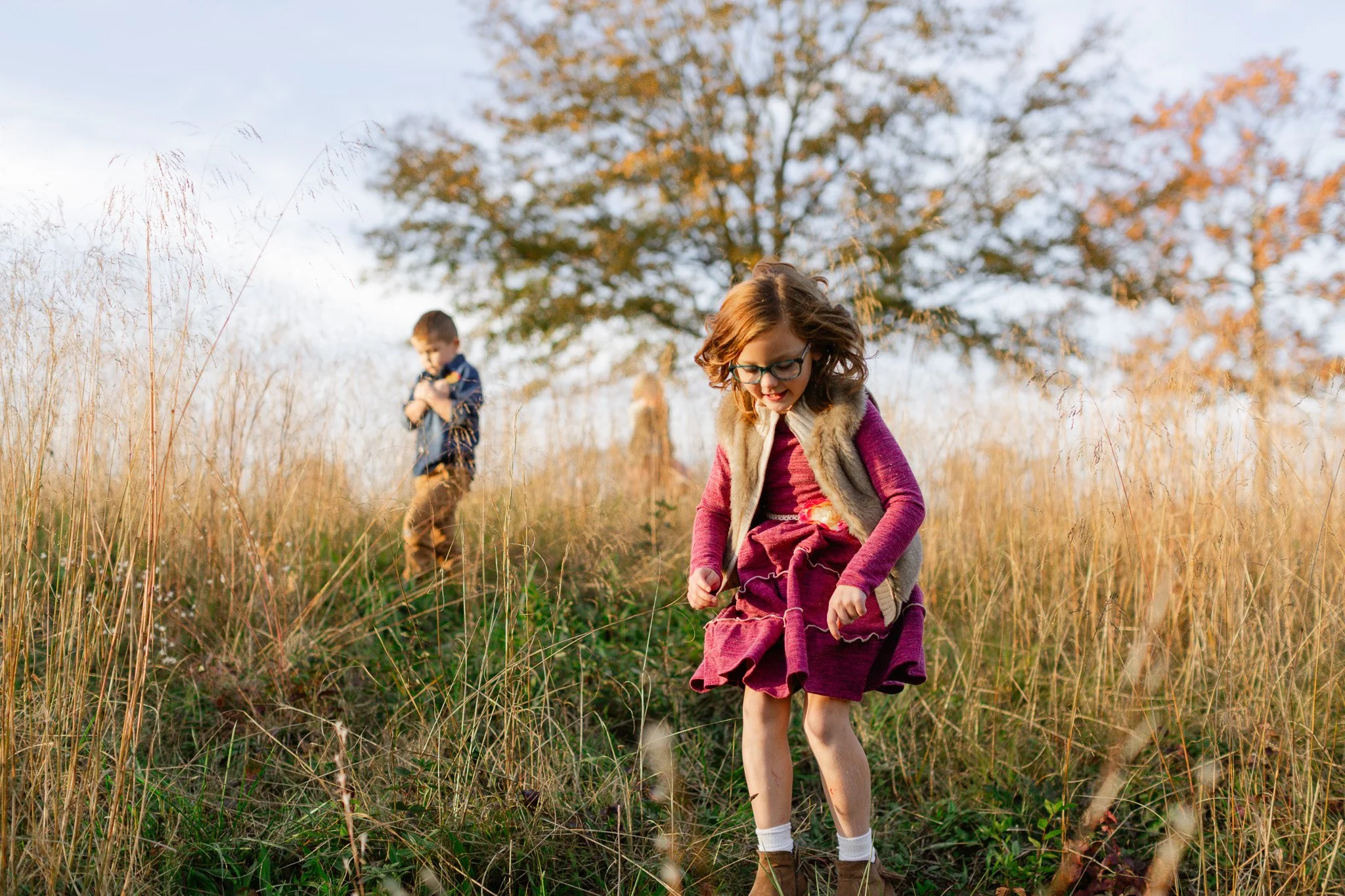 Sisters jumping in a field during golden hour photo shoot.