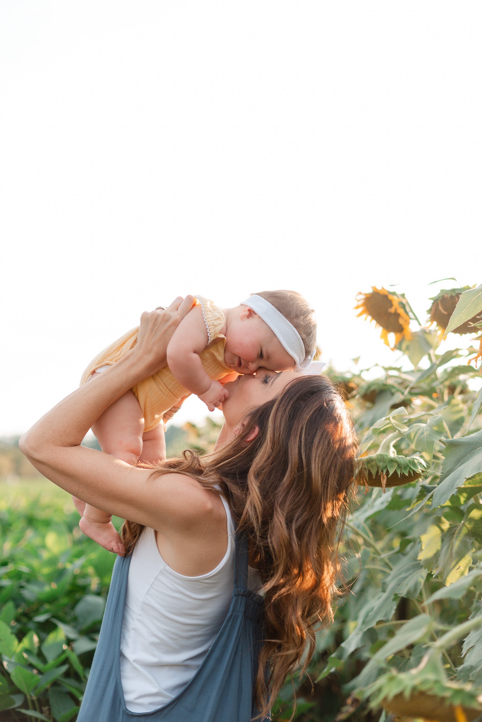 Mother and baby daughter in a sunflower field in Anderson South Carolina by Rios Tegen Photography