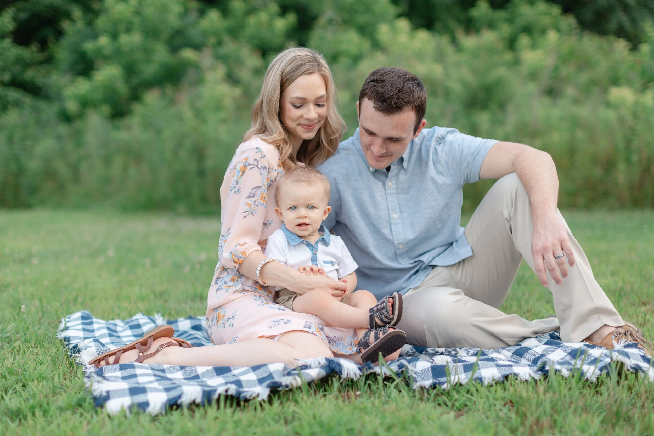 Family of three smiling at each other during natural light photo session in Clemson