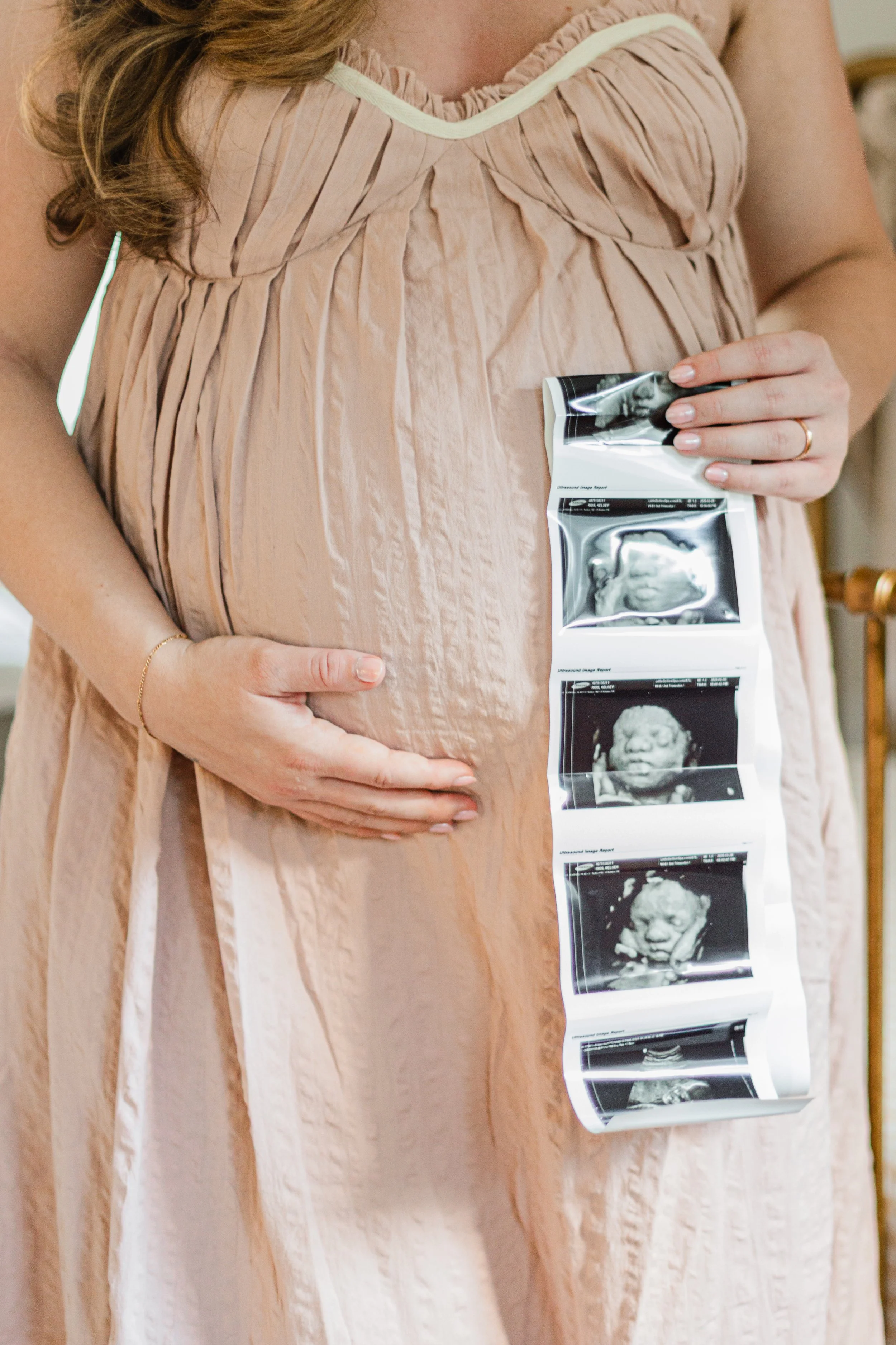 Woman holding sonogram photos during maternity photo session in Greenville SC