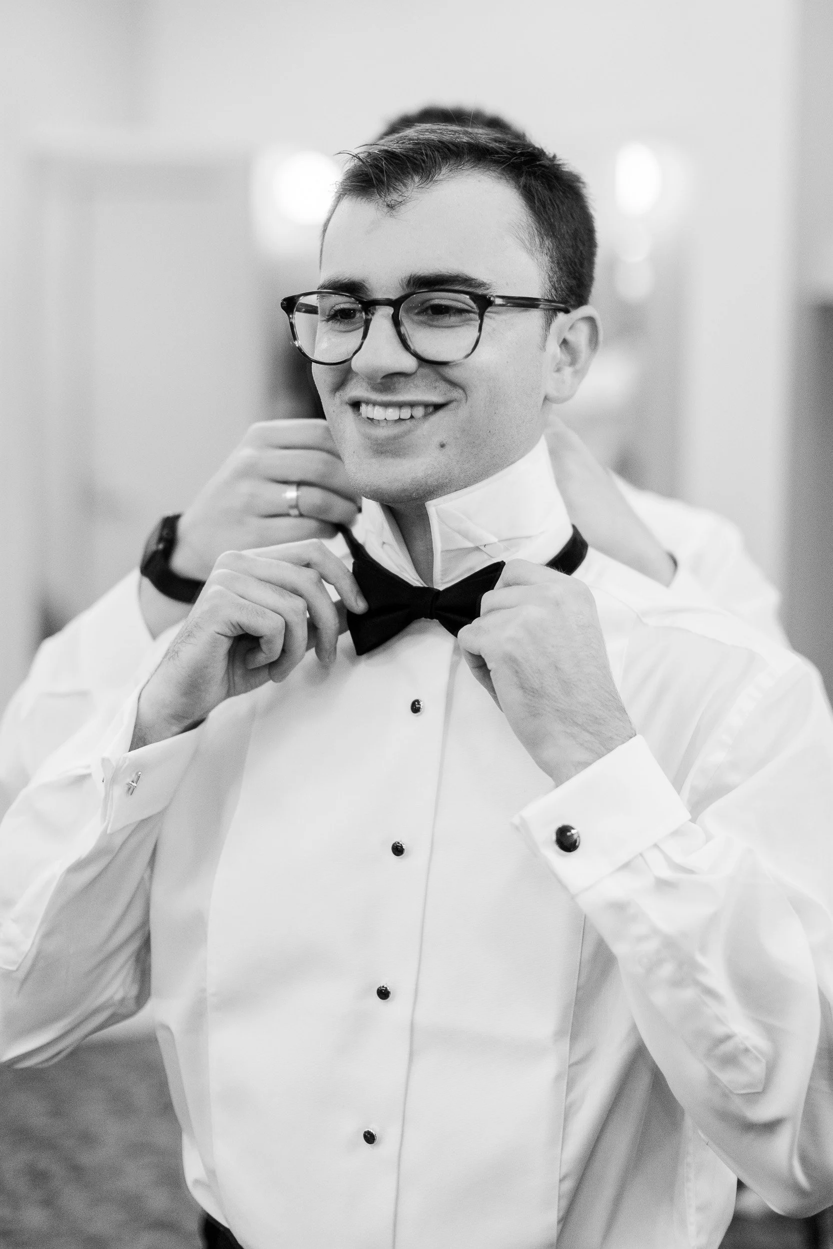 A man getting dressed for his wedding putting on his bow-tie for intimate downtown Greenville SC wedding.