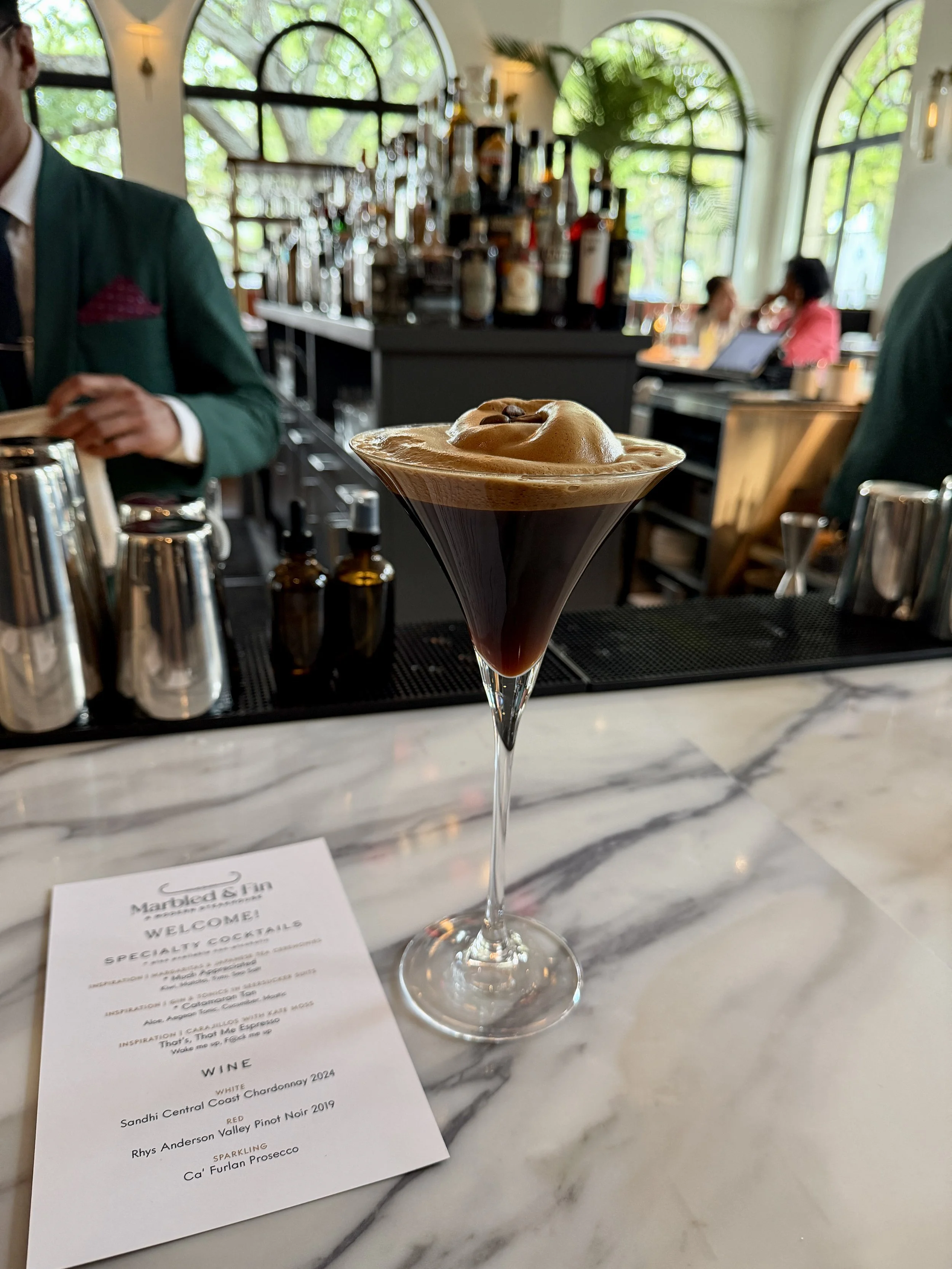 An espresso martini from Marbled & Fin in Savannah GA with a very foamy top and espresso beans as garnish
