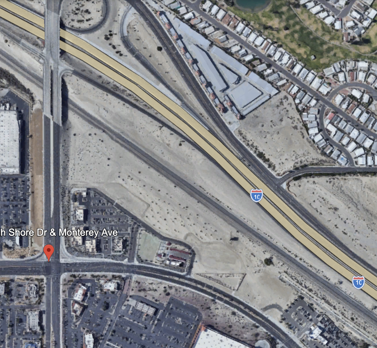 Satellite view of a highway interchange, including I-10, with surrounding residential and commercial areas, and a cleared construction site near South Shore Drive and Monterey Avenue.