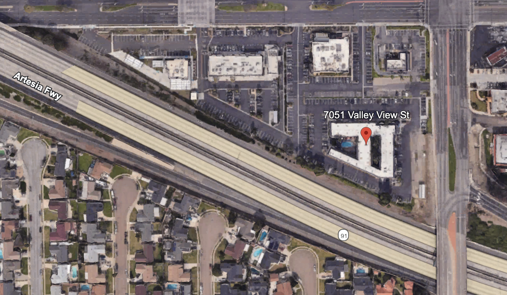 Satellite view of a map showing Artesia Freeway running diagonally, with a residential neighborhood below and commercial buildings above, labeled at 7051 Valley View Street.