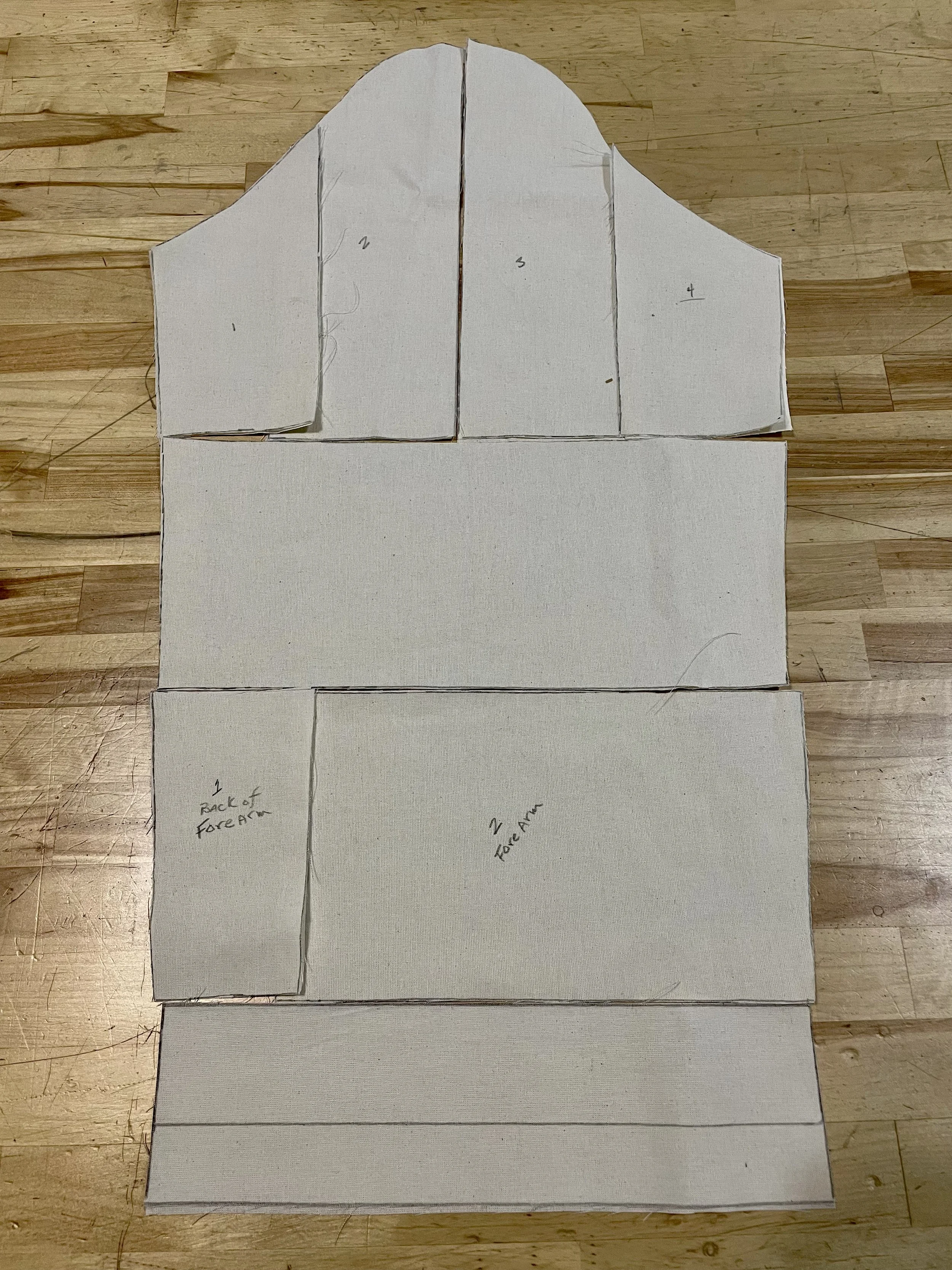 Uncut pattern pieces for sewing, labeled with numbers and instructions, laid out on a wooden surface.