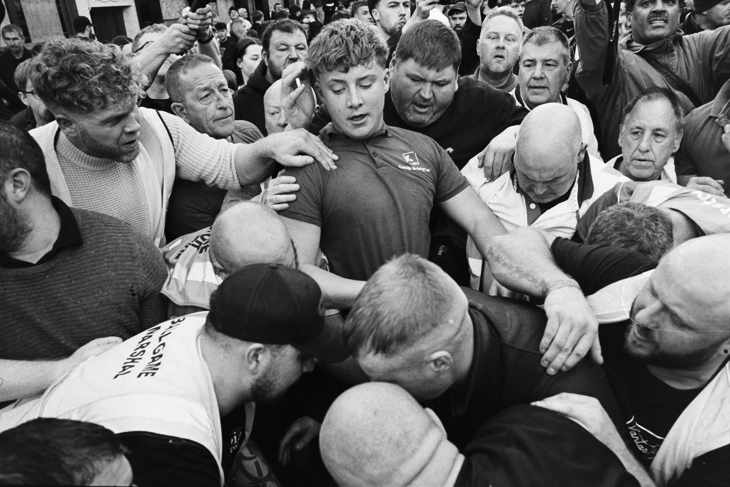 A large group of people engaged in a physical confrontation, with some individuals pushing and grabbing each other, in a chaotic scene.