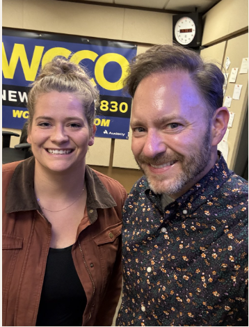 A woman and a man taking a selfie in a radio station studio with a WCQC sign in the background.