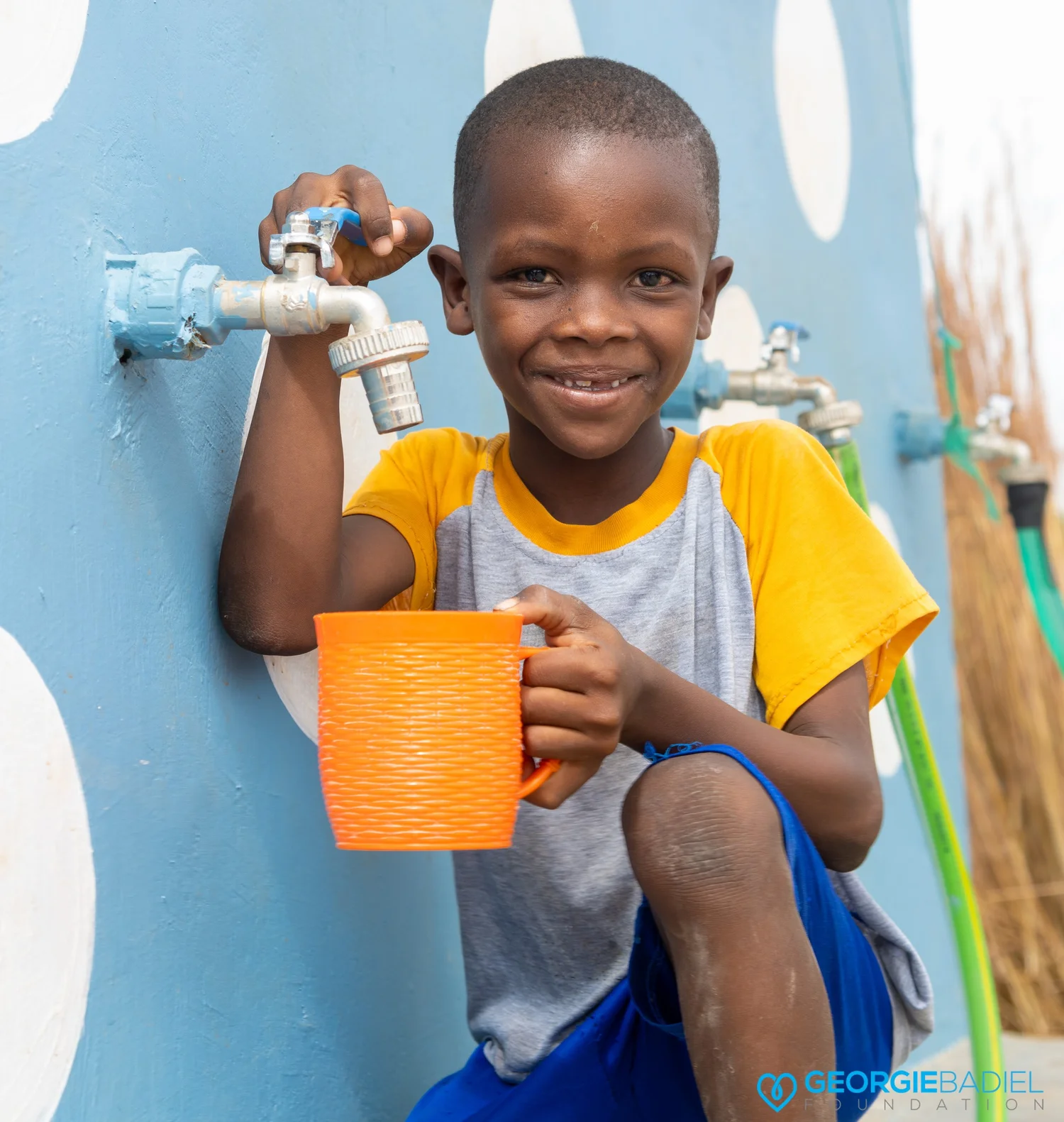 Child filling a cup at water spout