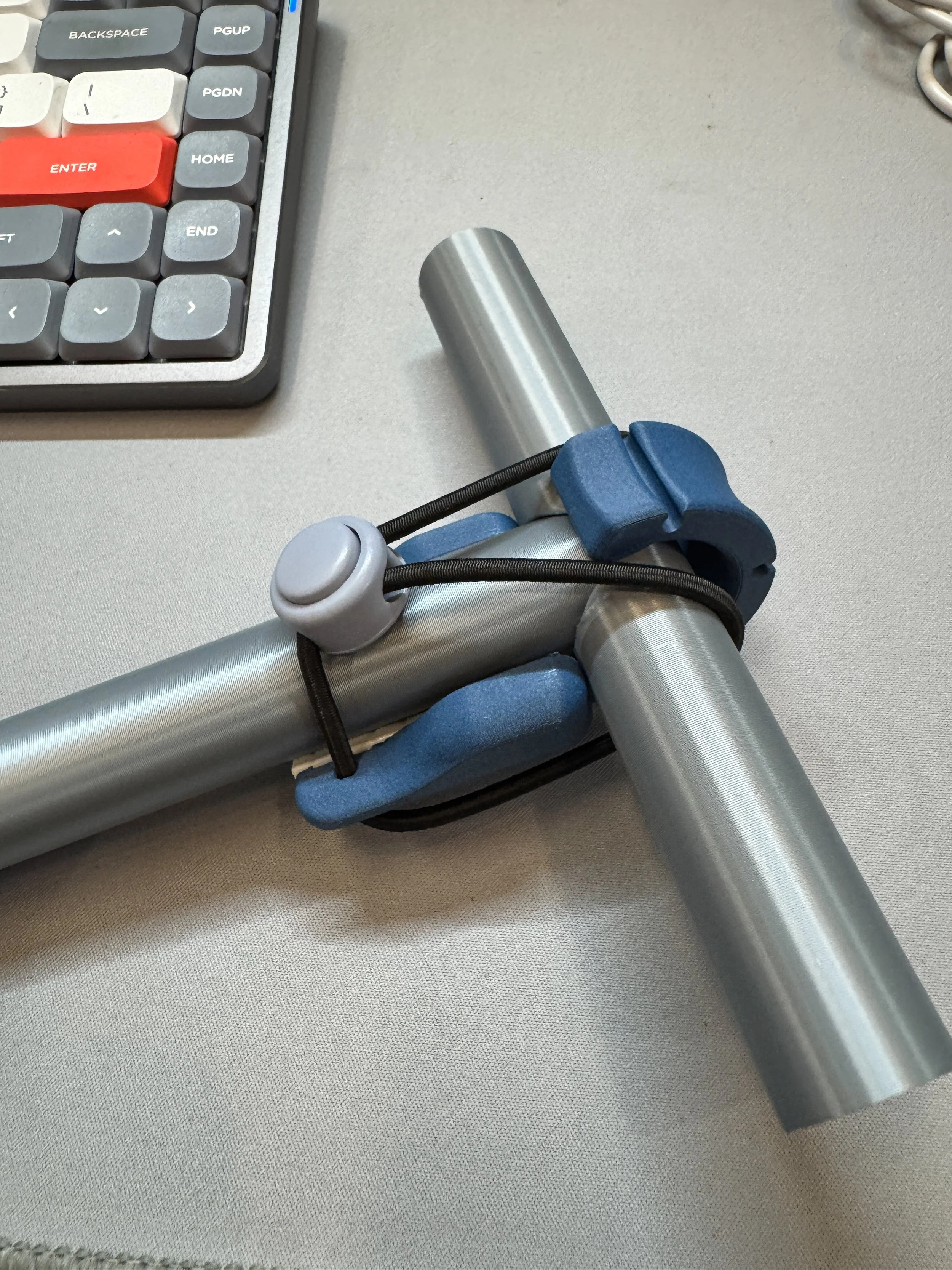 Part of a computer keyboard, a cylindrical metal object, and a blue wrapped item on a beige fabric surface.