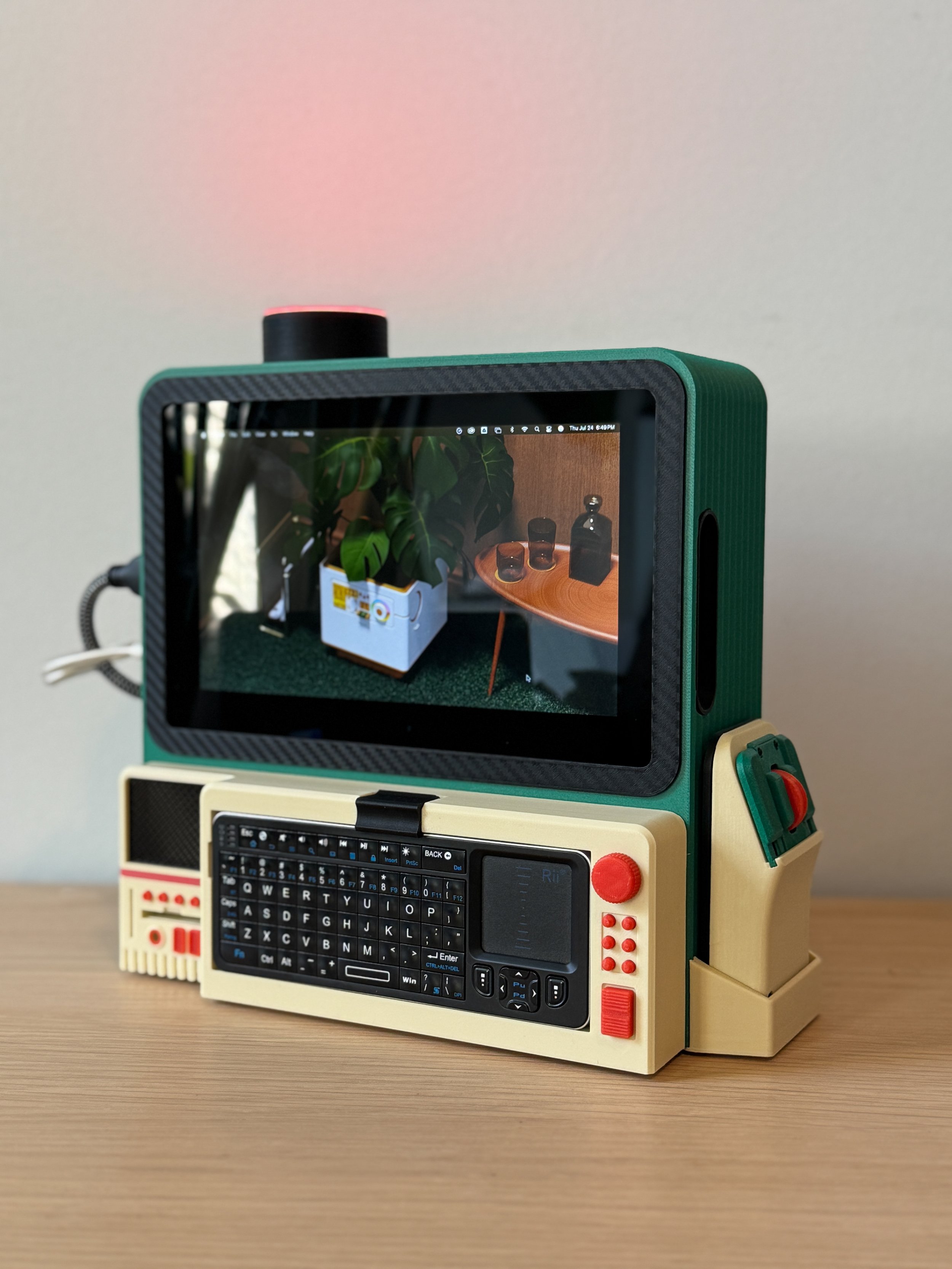 A toy computer with a keyboard, small screen, and various colorful buttons, sitting on a wooden surface.