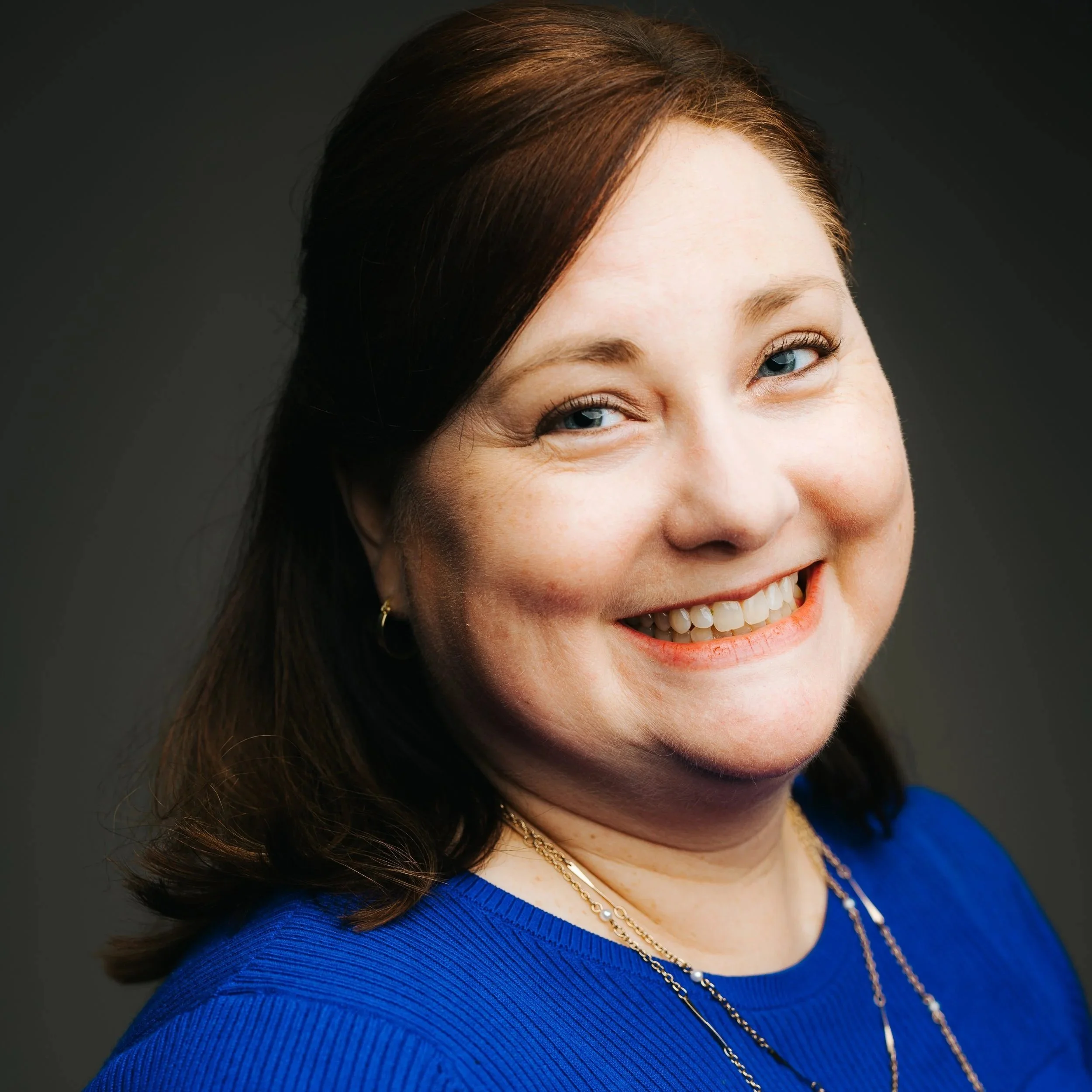 Robin Miura, a white woman with red-brown hair pulled back and wearing a blue shirt.
