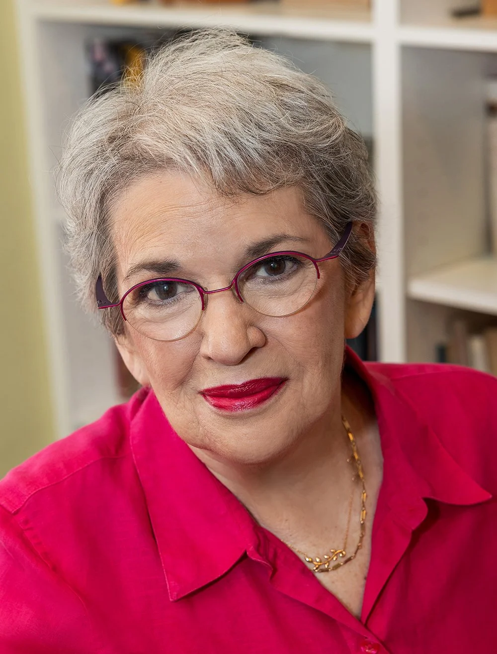 Photo of Enid Shomer wearing pink glasses and a pink collared blouse