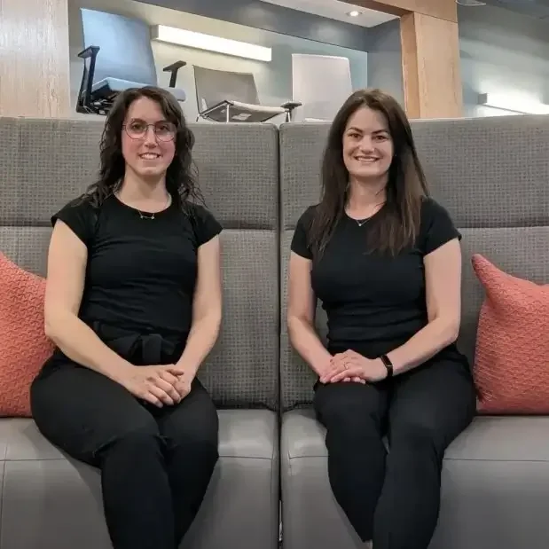 Two women sitting on grey sofa