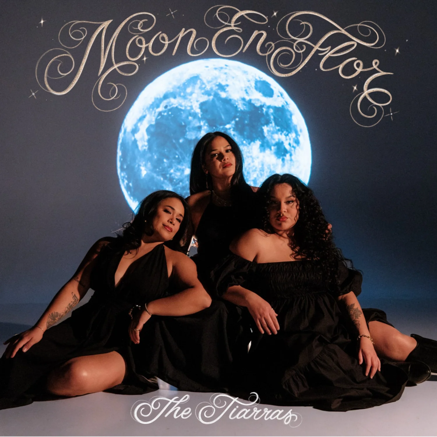The three members of Austin sister trio The Tiarras in black dresses beneath a bright blue moon on the Moon En Flor album cover