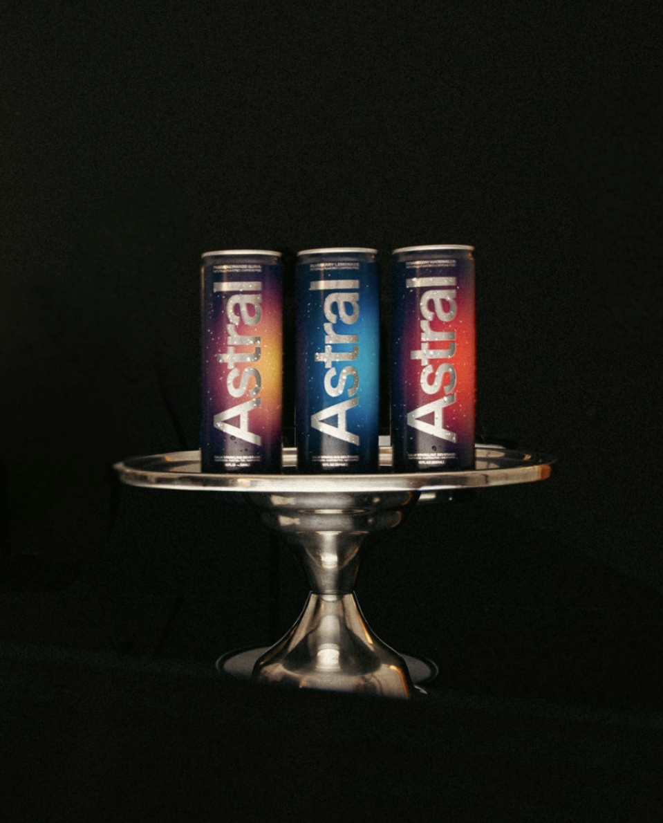 Three cans of Astro energy drink on a silver tray against a black background.