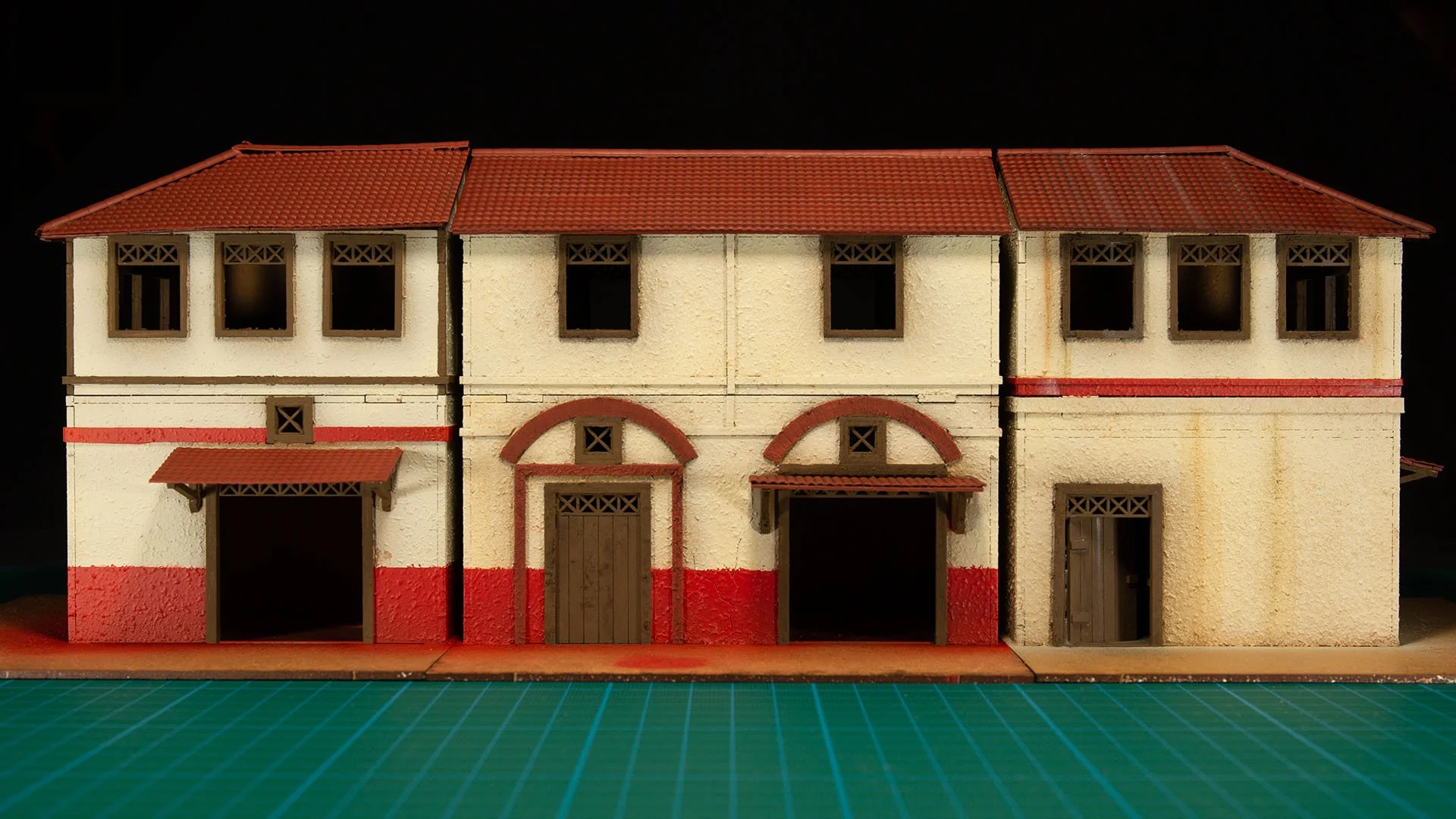 Three fully painted MDF model buildings featuring cream walls, red lower borders, brown wooden doors, and red tiled roofs.