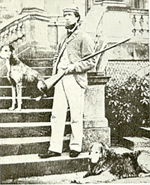 a old photo of a man with a gun standing by a golden retriever