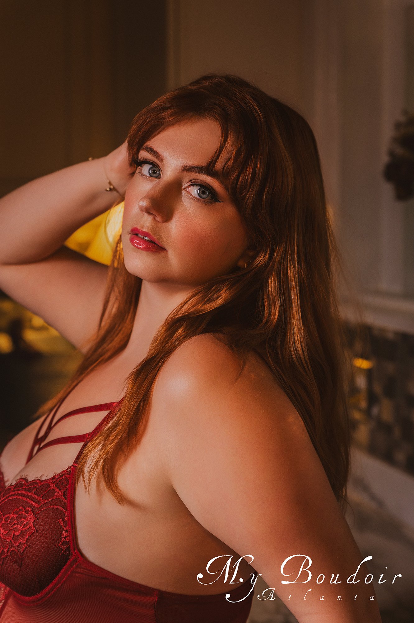 Person with red hair in a red lace outfit posing indoors.