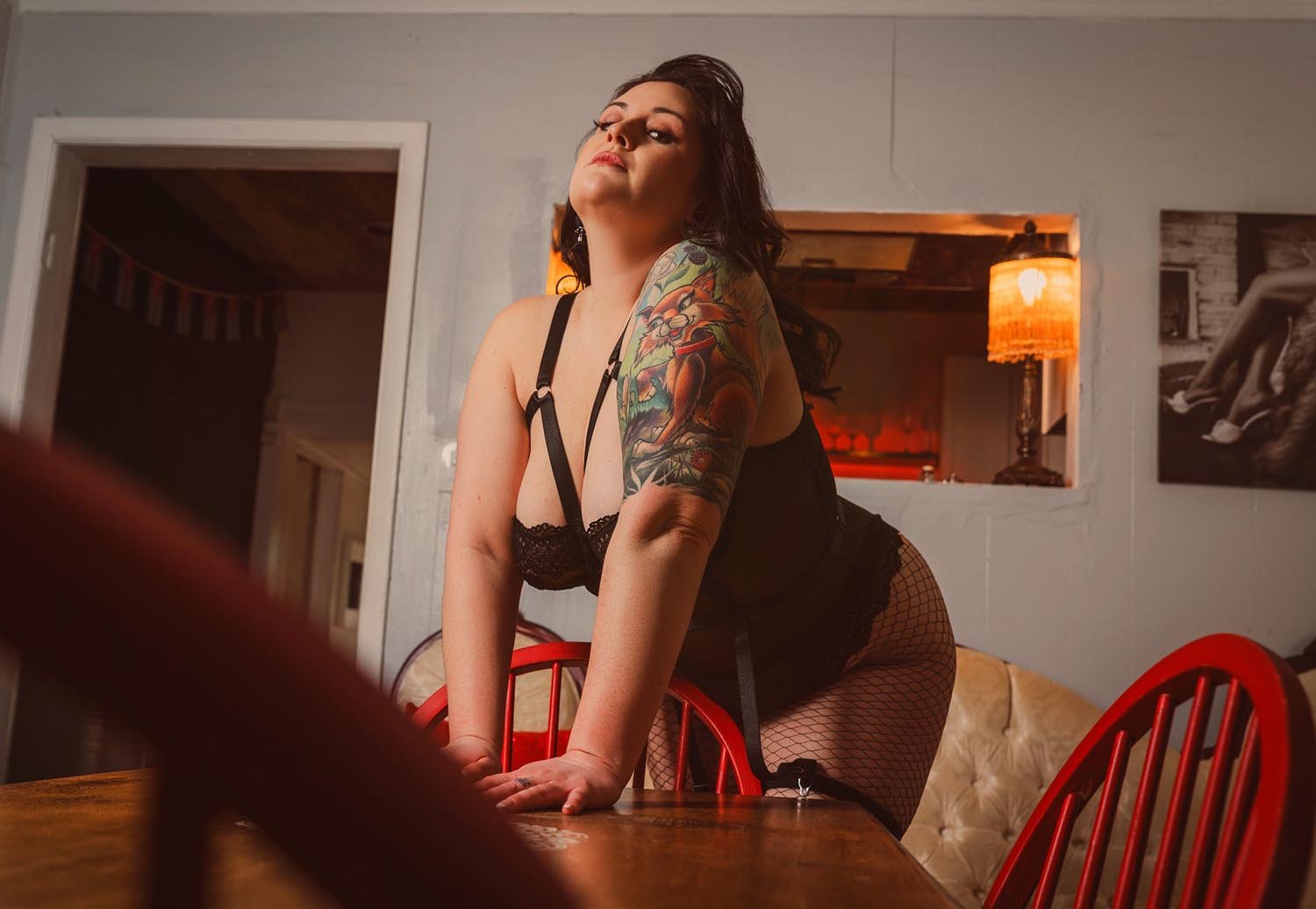 Curvy tattooed woman poses in the West End for boudoir photos in dining room scene.