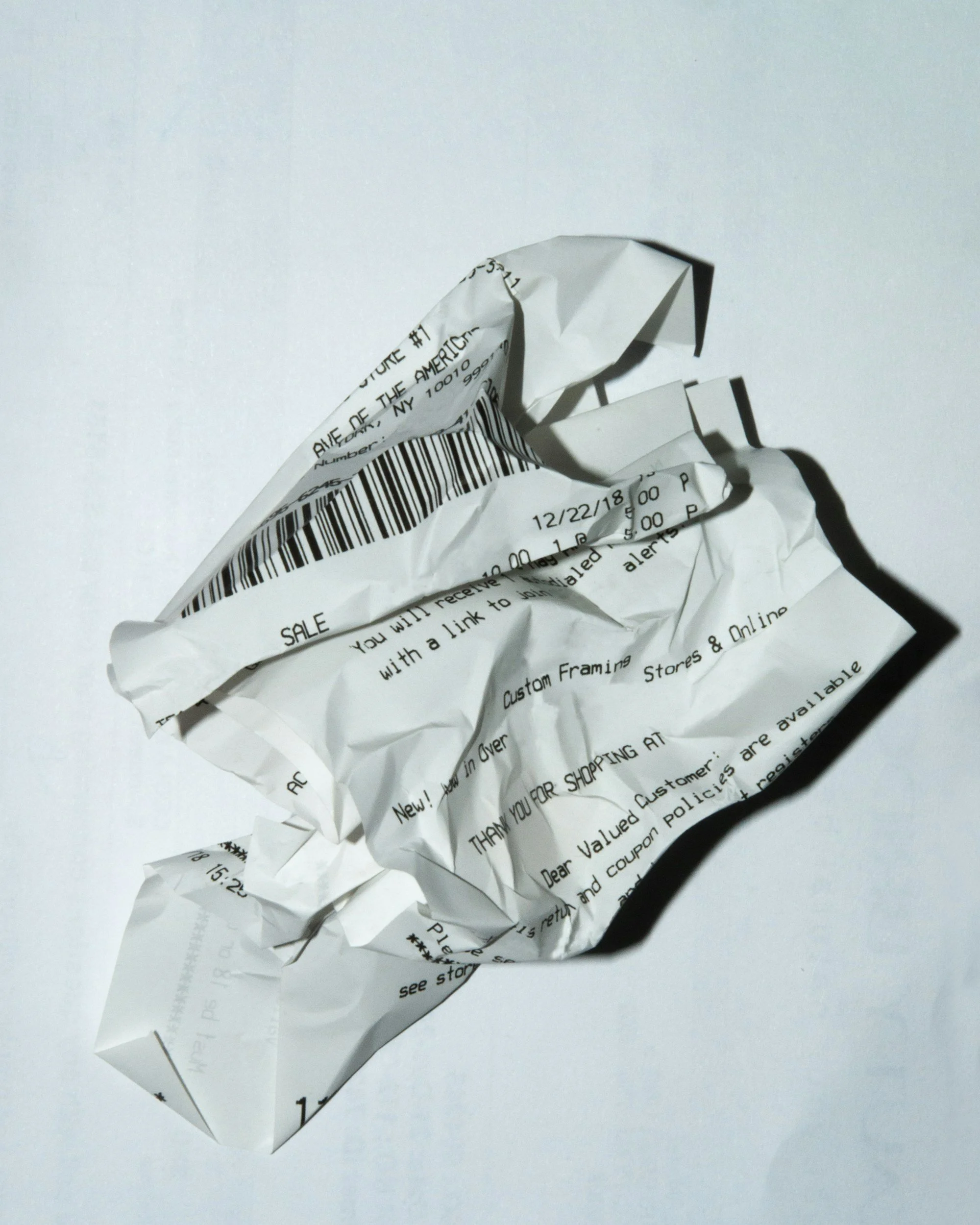 Crumpled receipt with printed text and barcode on white background
