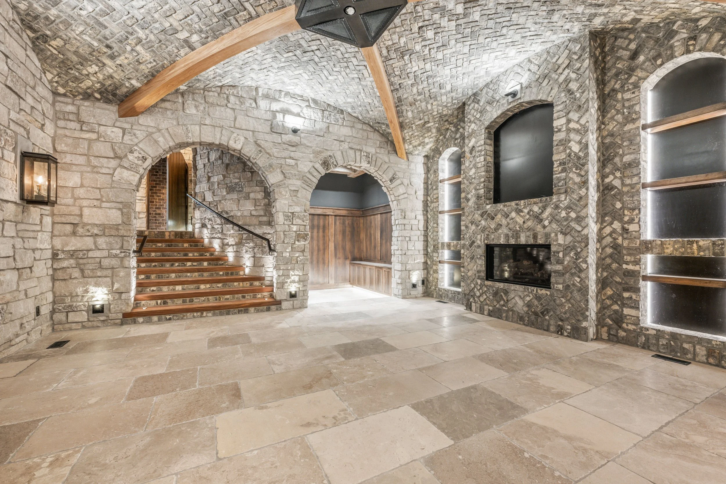 Finished stone archway bar area with vaulted ceiling and custom lighting in a completed luxury home